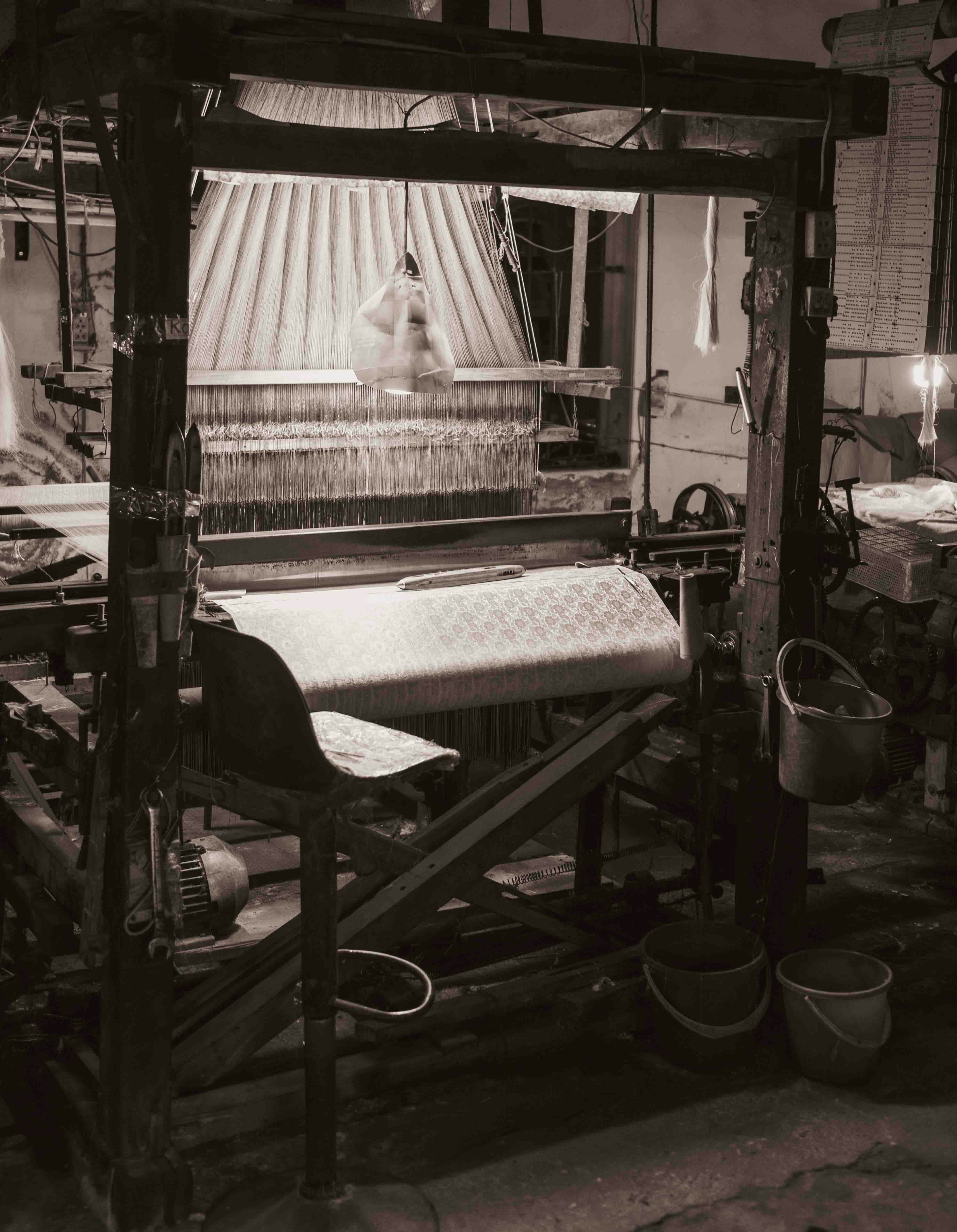 An old weaving loom with a chair in a workshop.