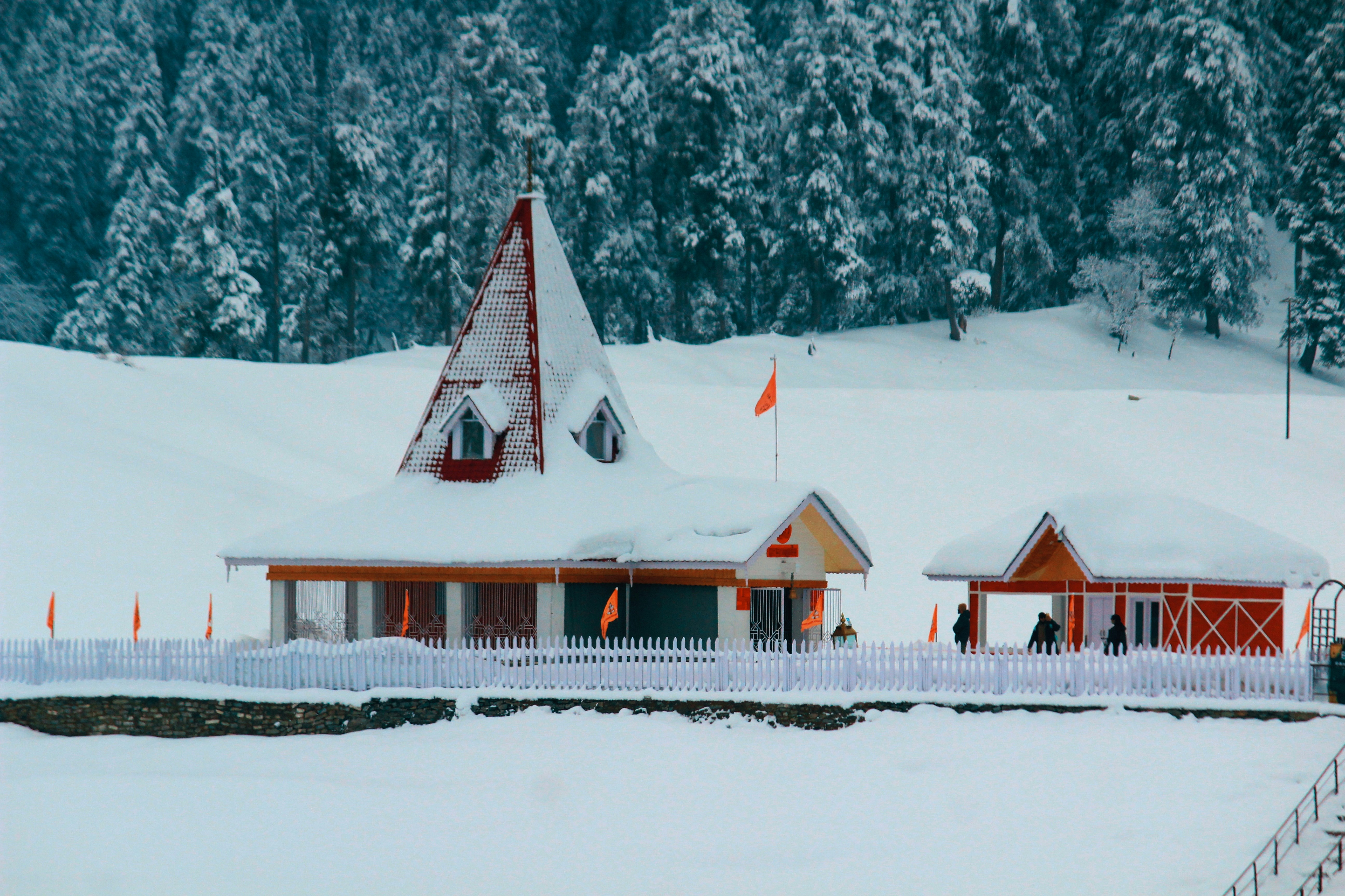 Snow-covered buildings with orange flags in a winter landscape.