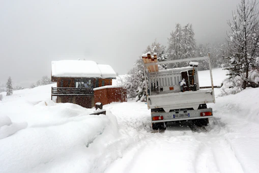 A truck carrying wood drives on a snowy road.