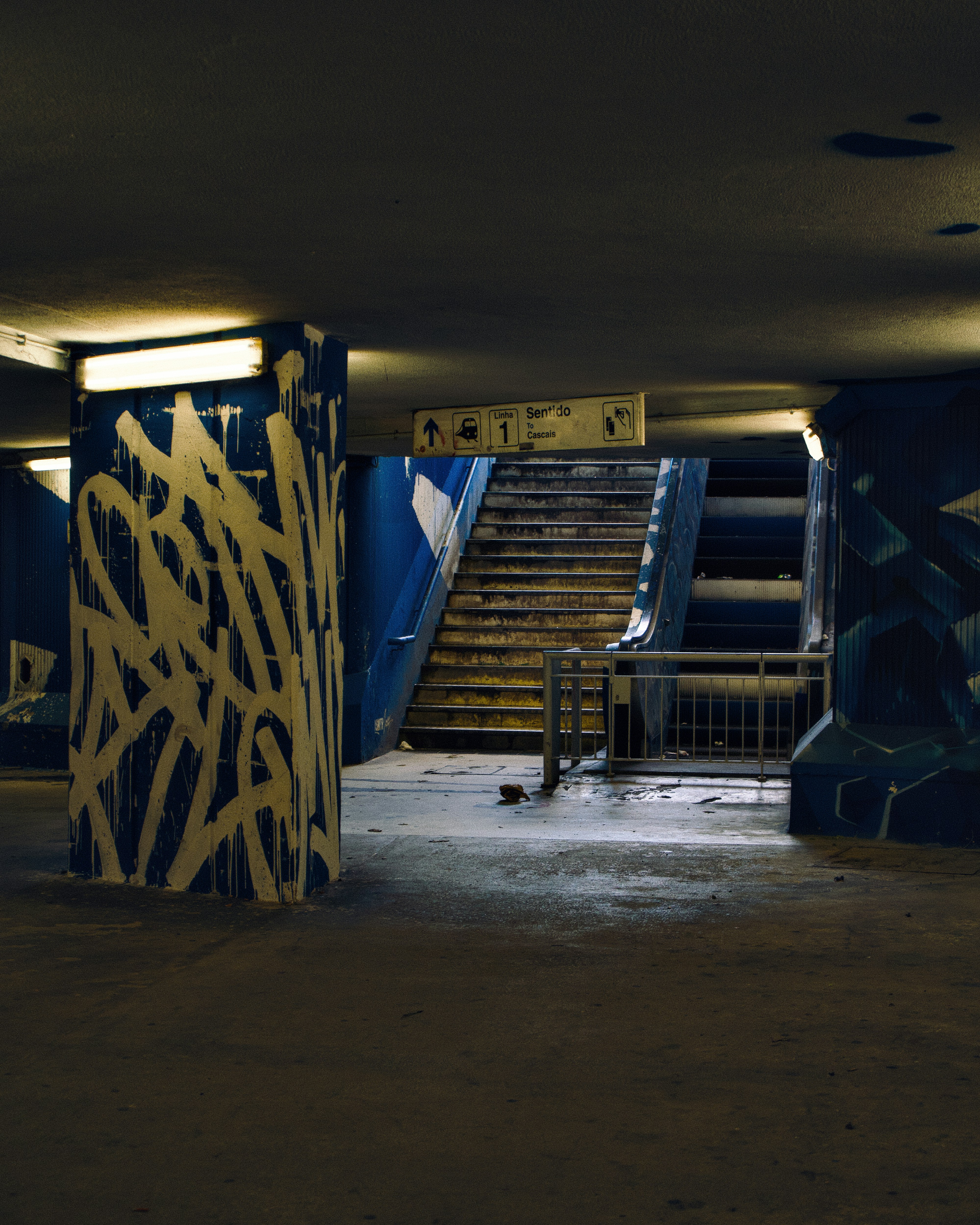 Un pilier couvert de graffitis dans une station de métro sombre.