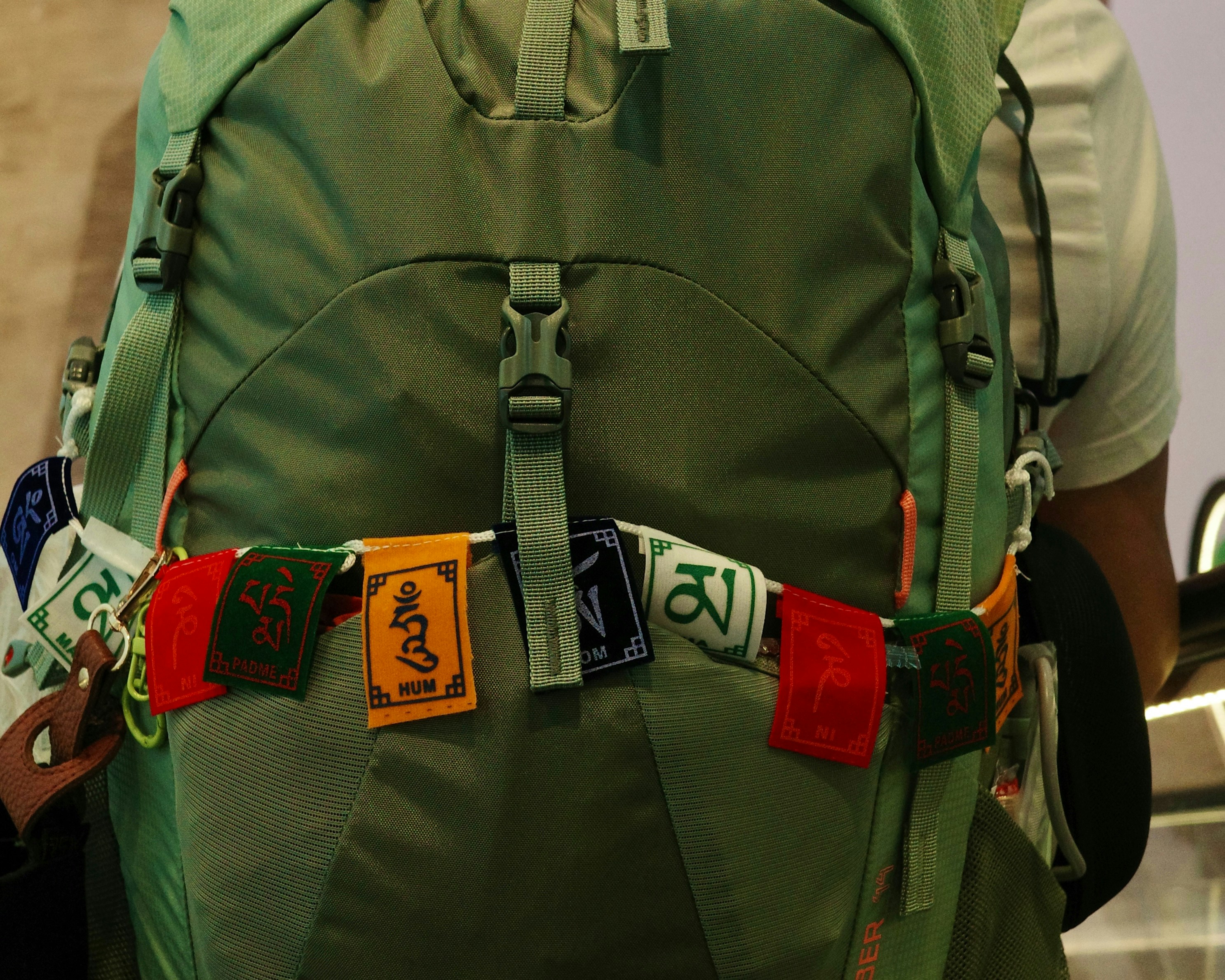 Mochila verde con banderas de oración adheridas