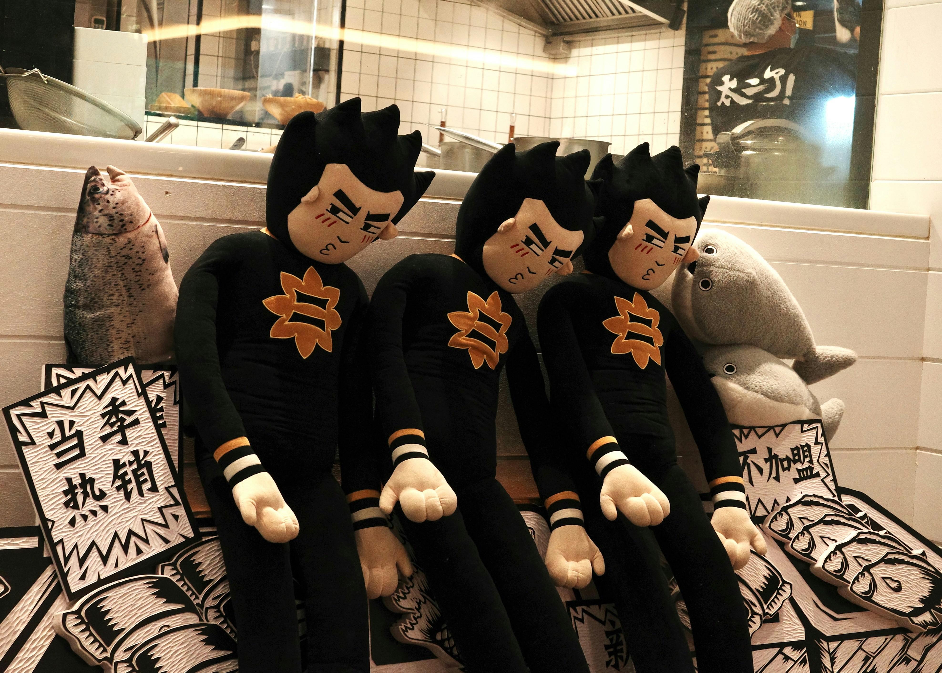 Tres peluches con trajes negros y emblemas naranjas