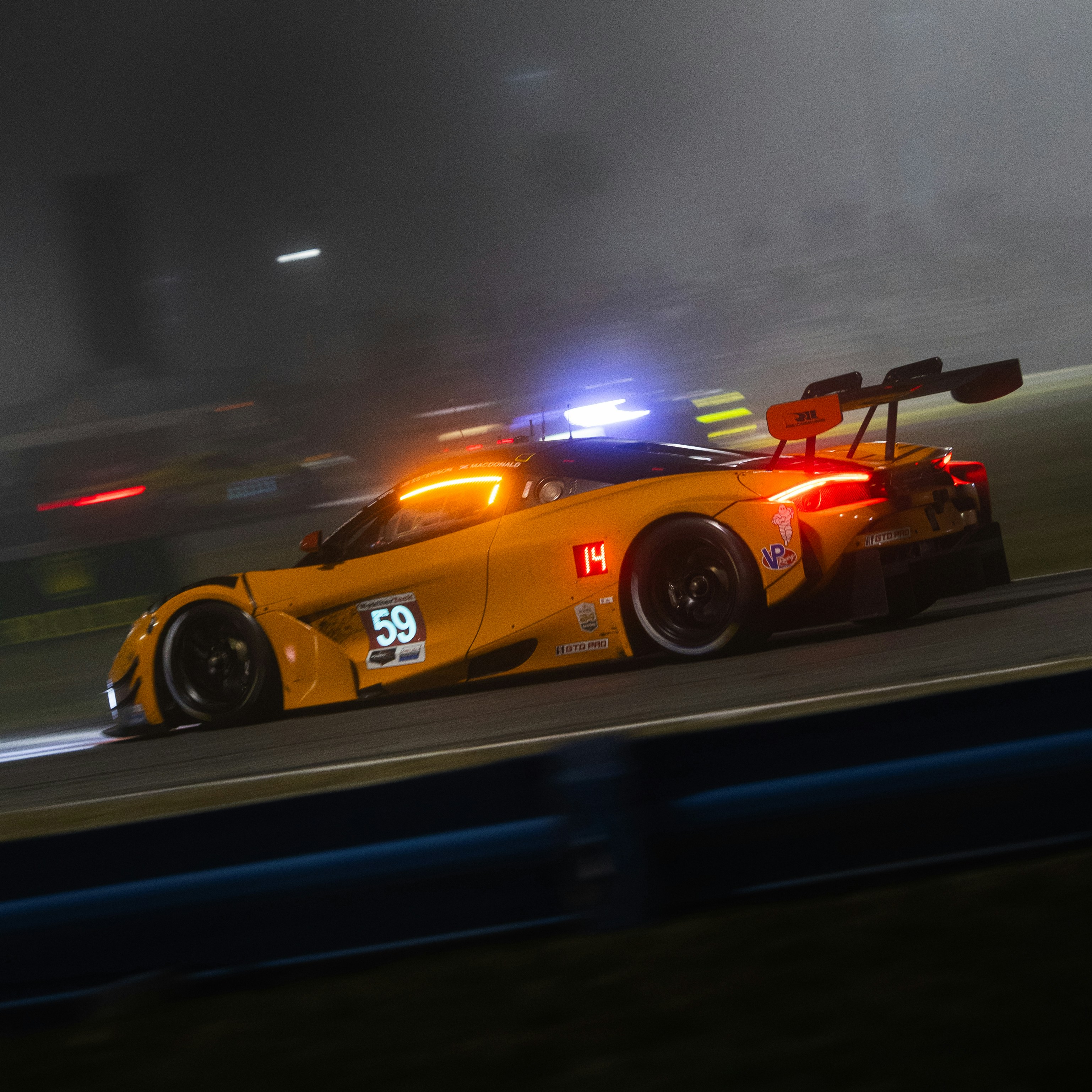 Orange race car with blue and orange lights at night