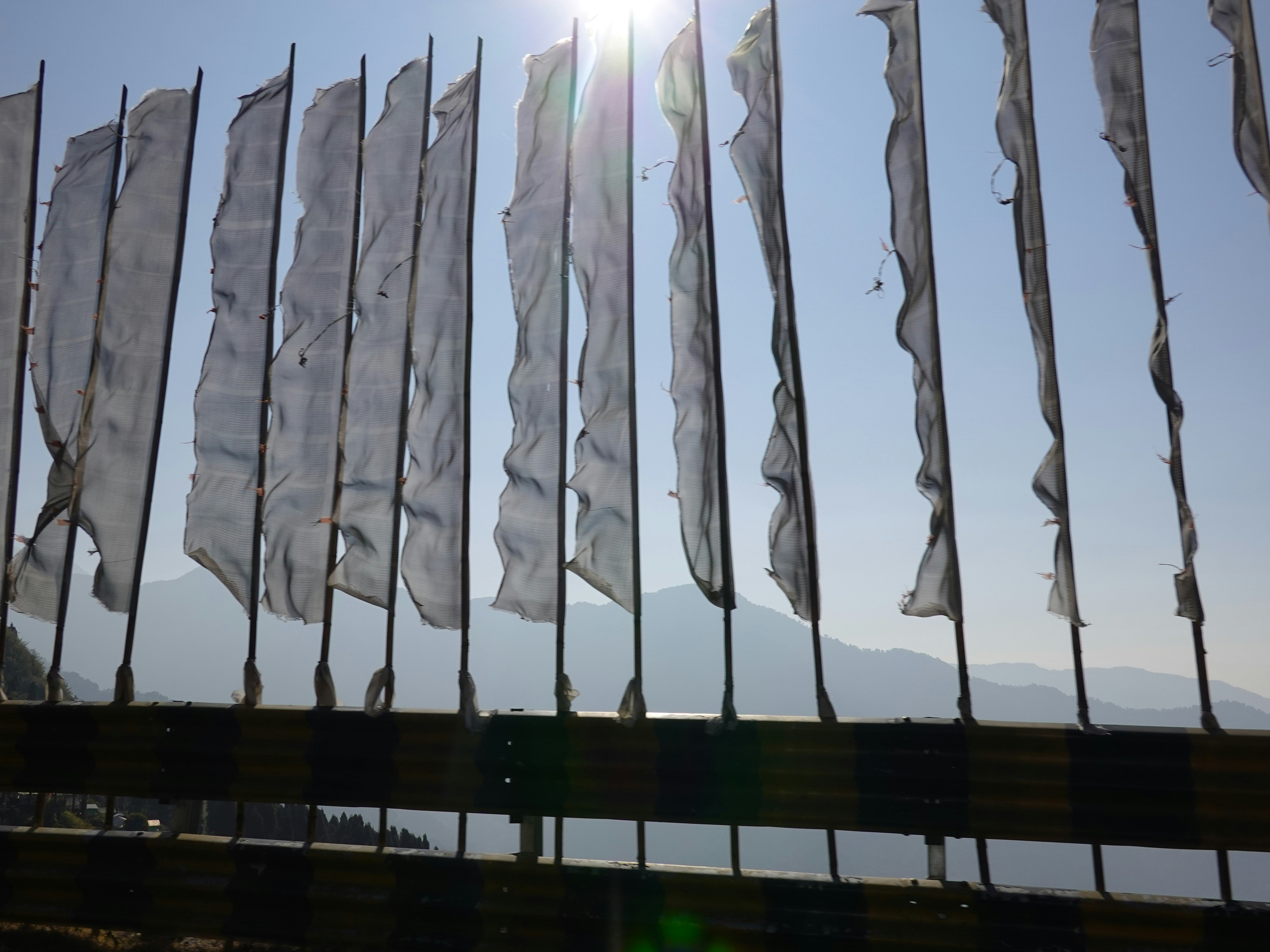 White prayer flags flutter against a bright sky.