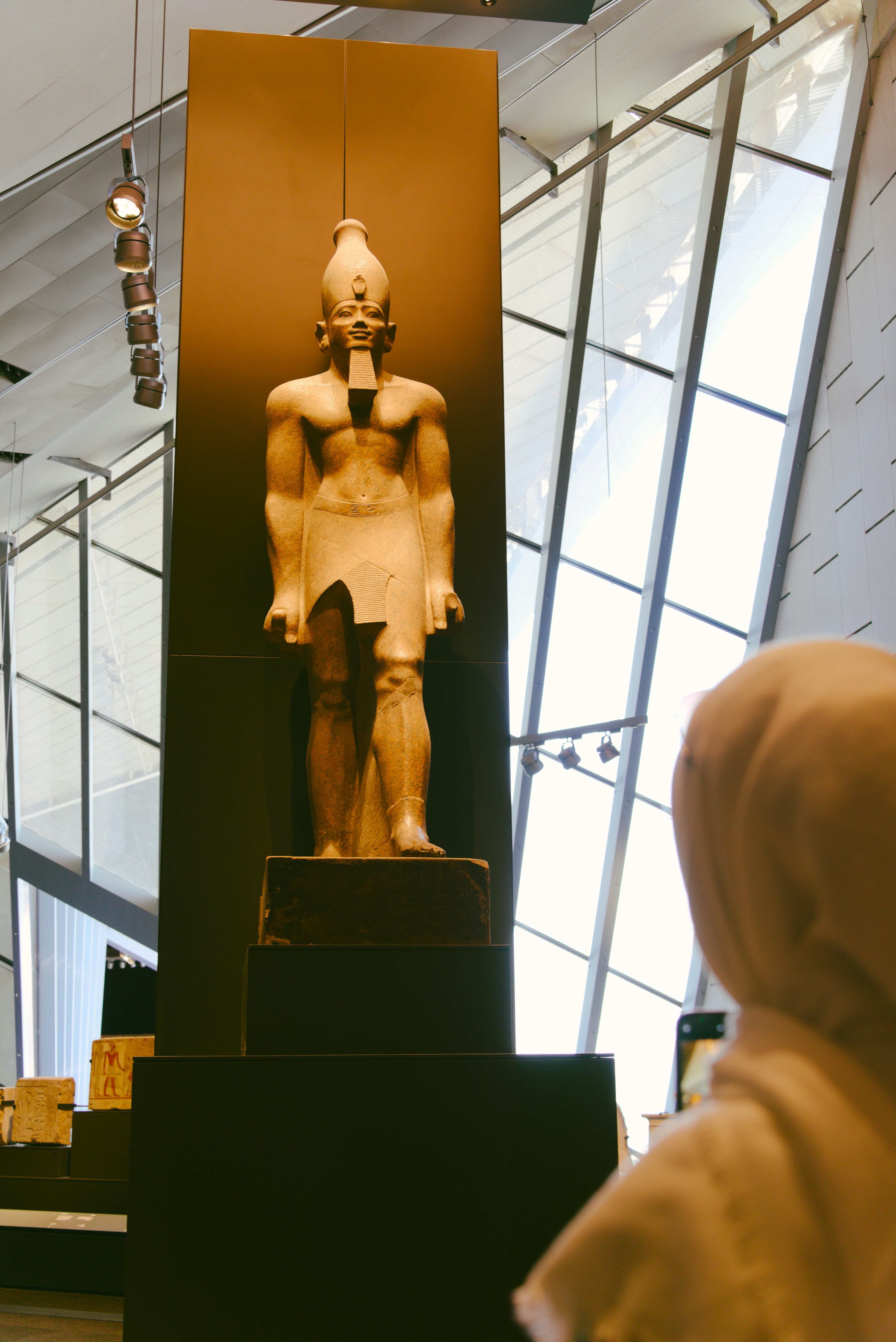 Ancient egyptian statue displayed in a modern museum setting.