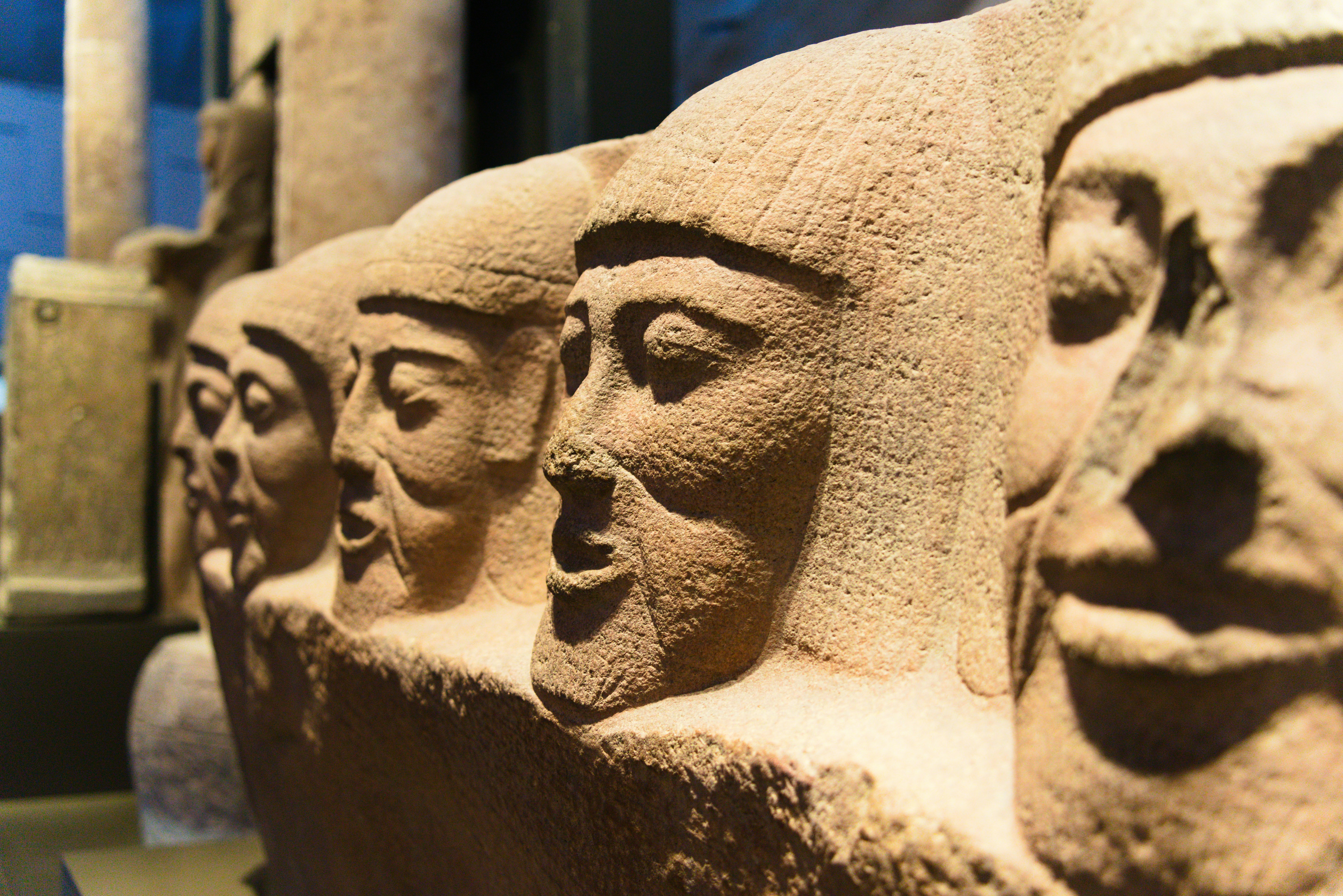 Row of ancient stone carved faces in profile.