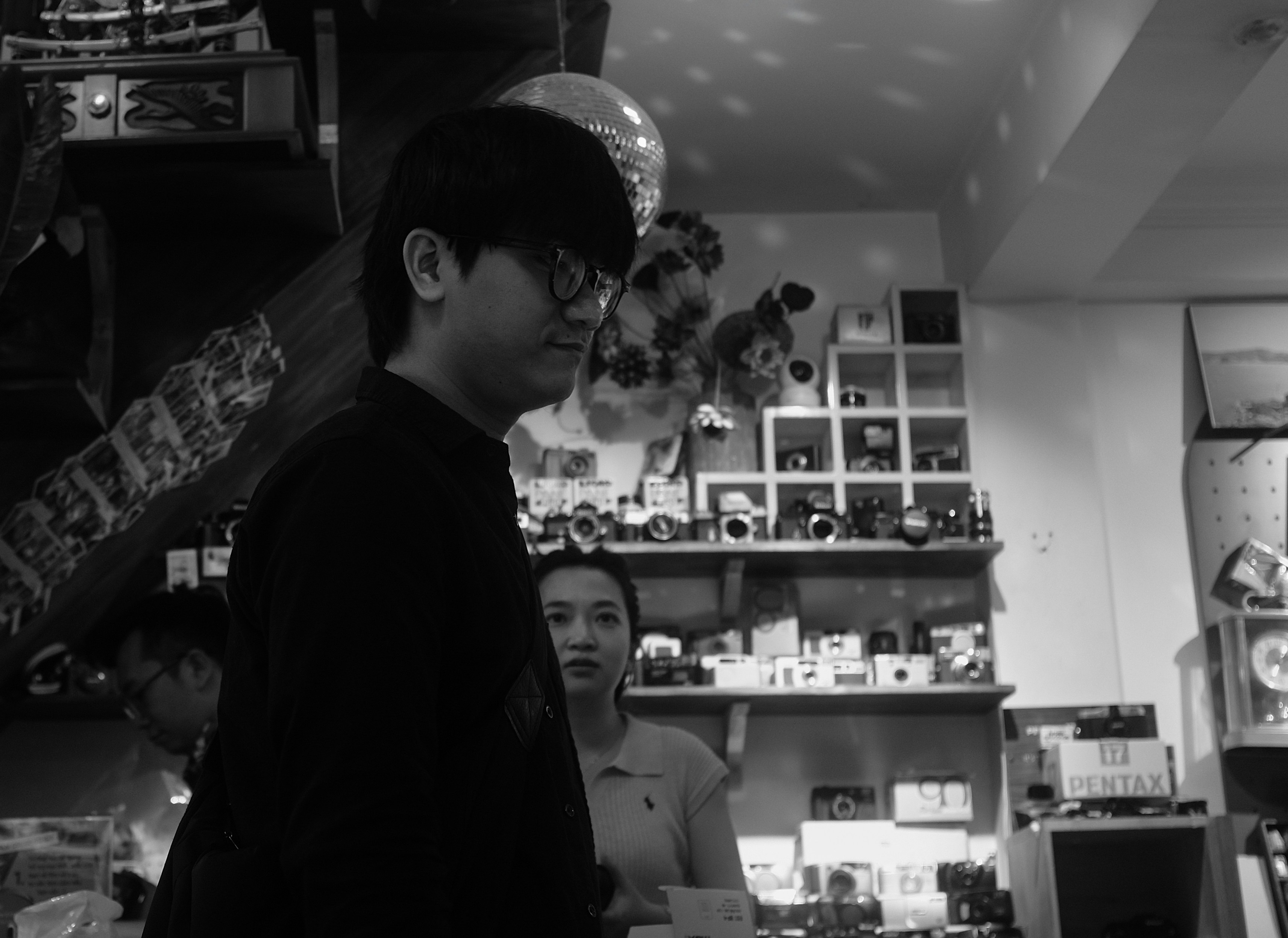 Young man with glasses in a shop with cameras.