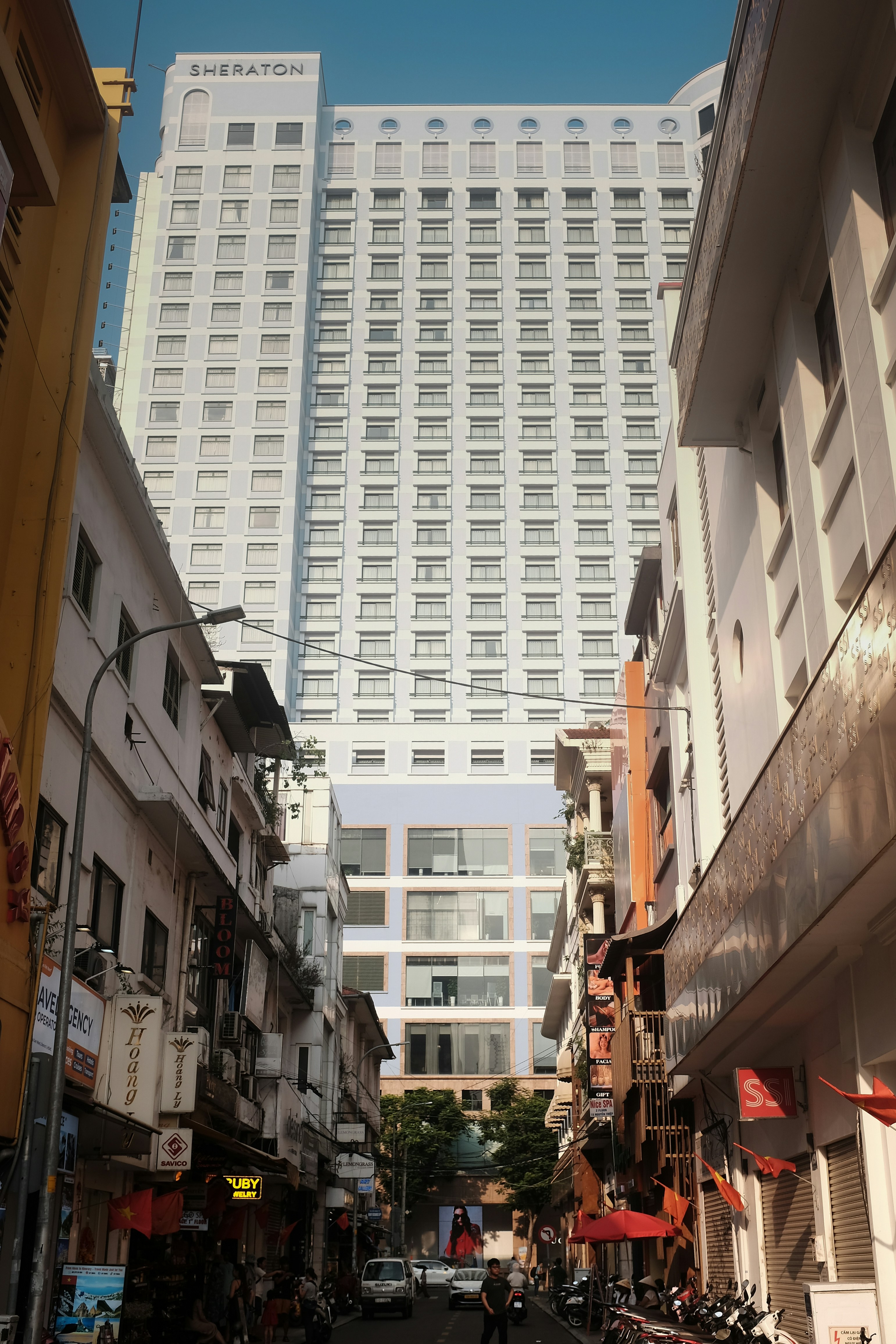 Tall sheraton hotel building towers over narrow street.