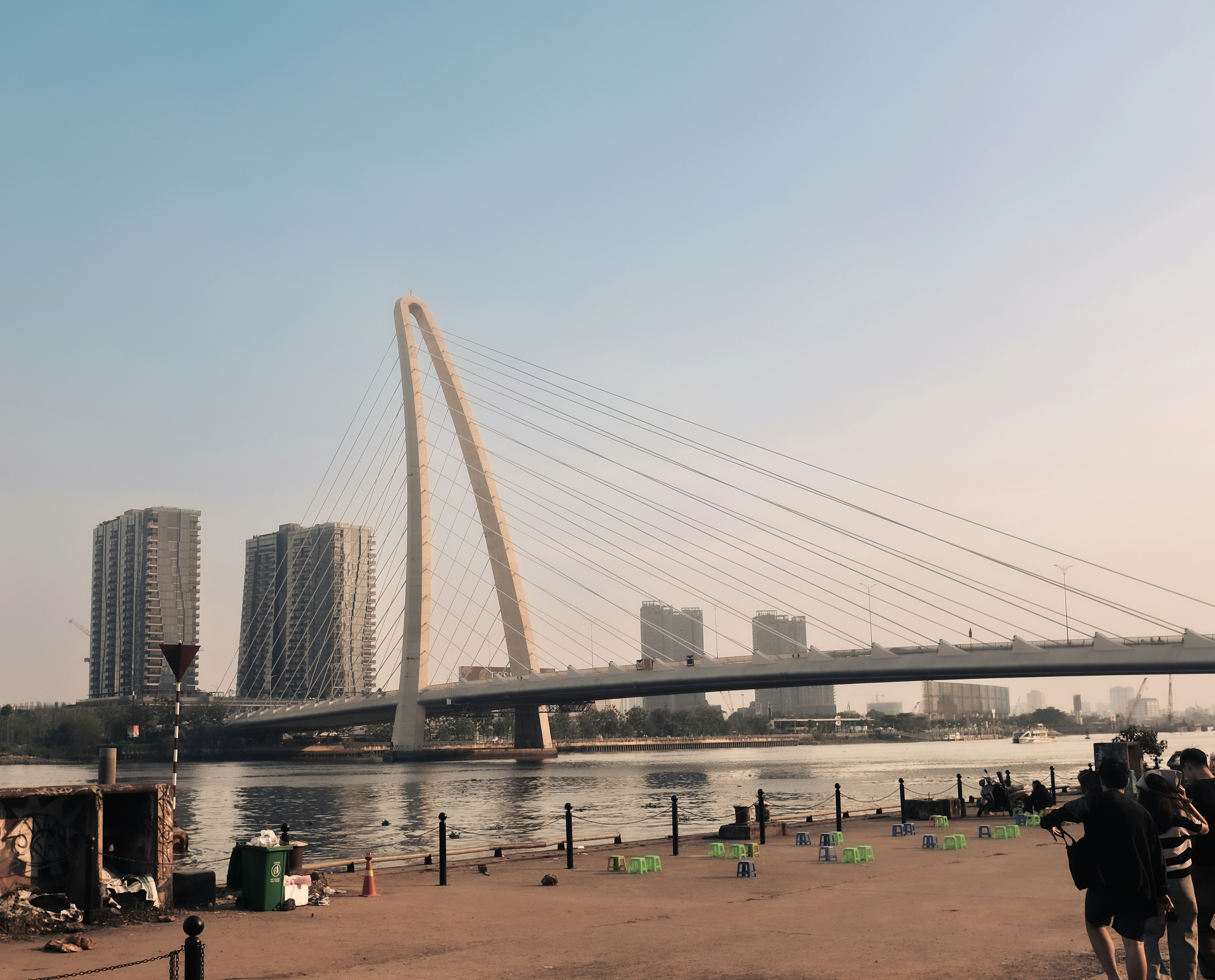 Modern bridge spans river with city skyline background