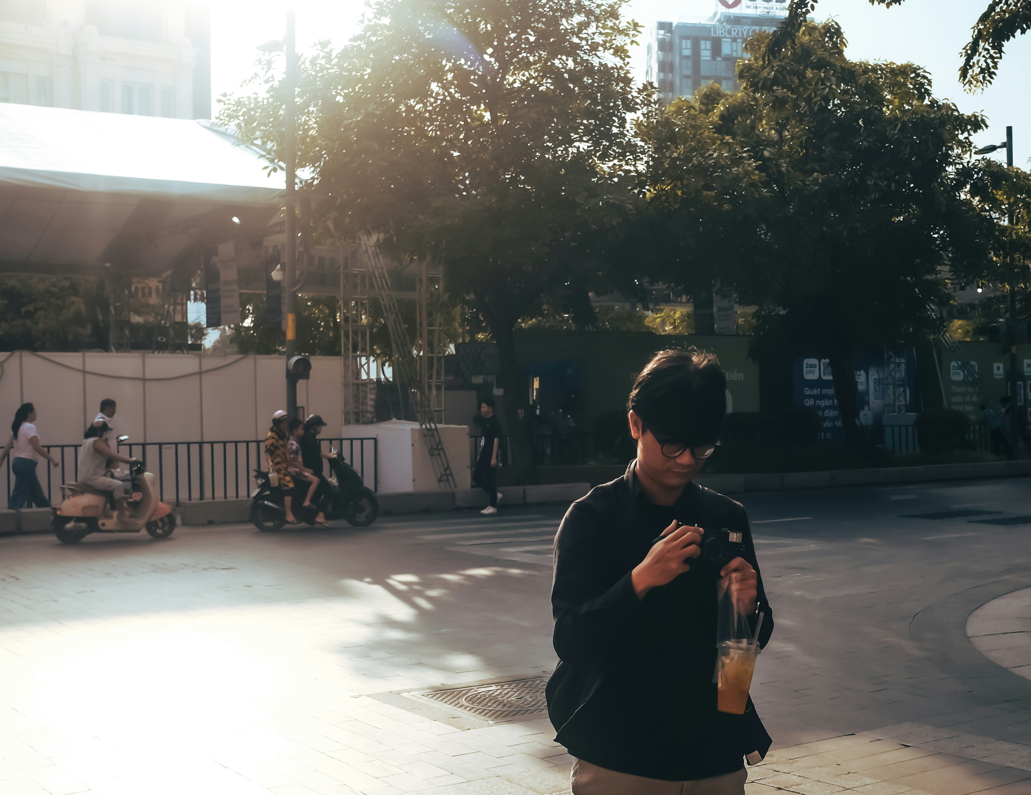 Man in black jacket holding a drink outdoors.