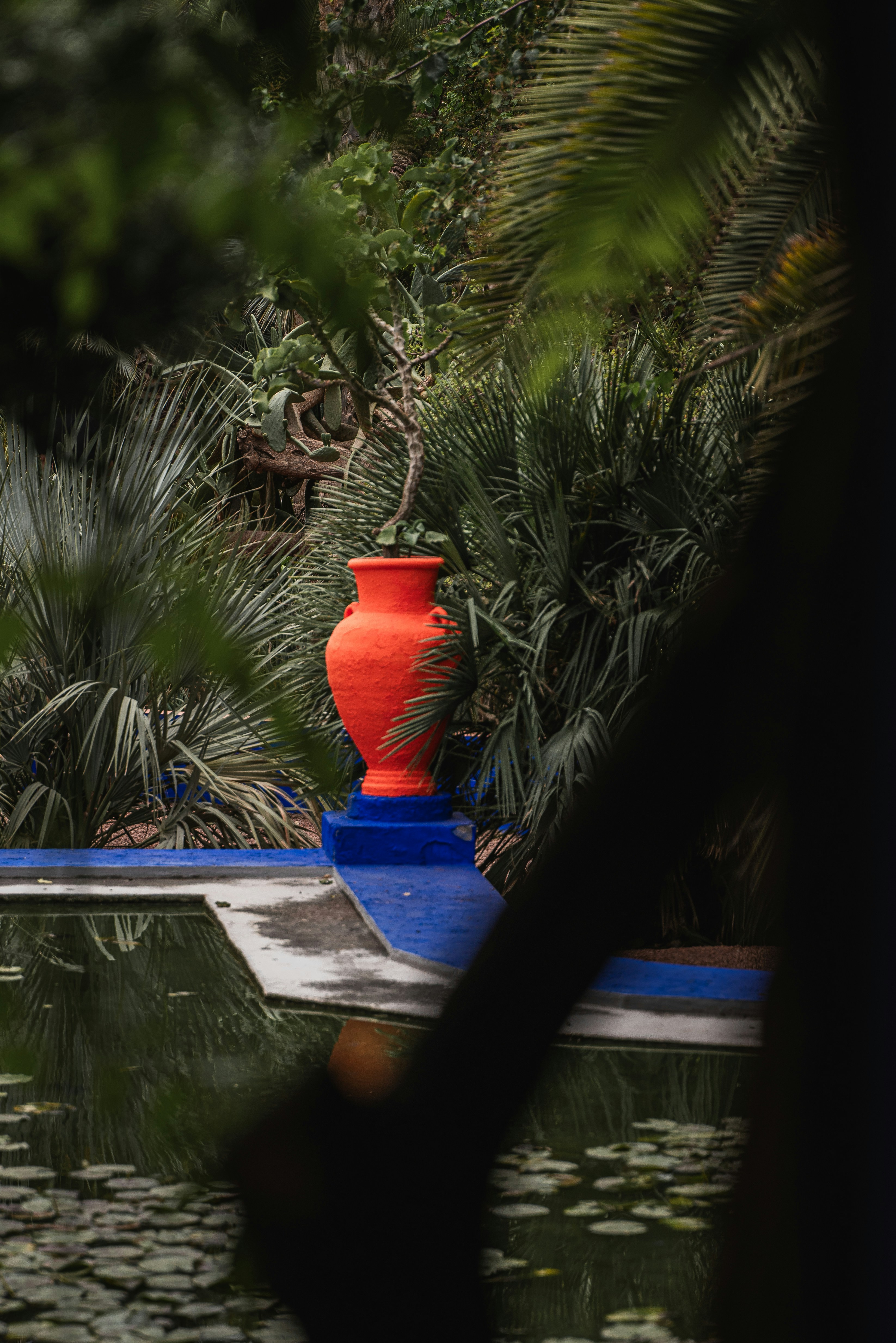Bright orange vase on a blue structure near water