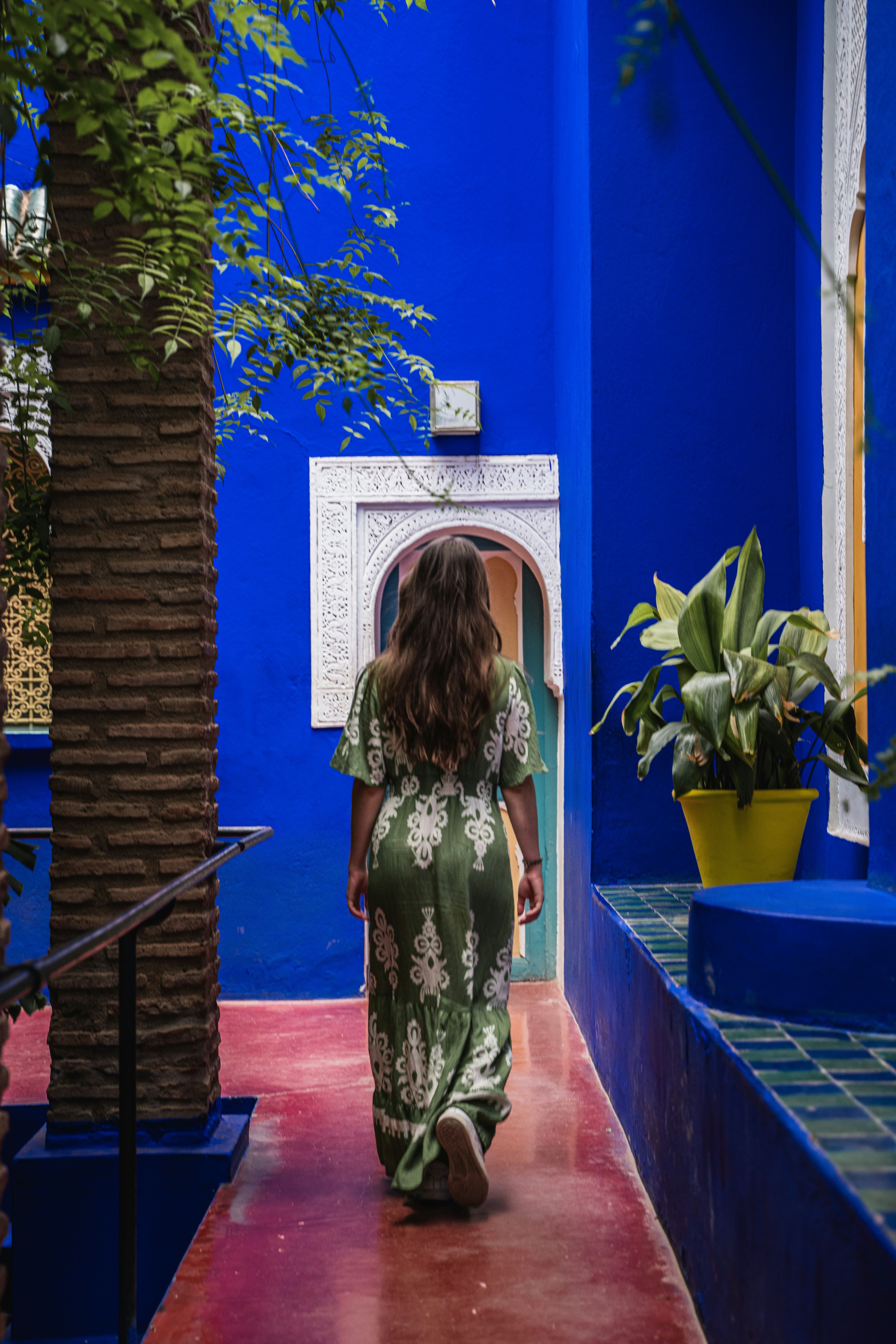 Woman in green dress walks down blue corridor