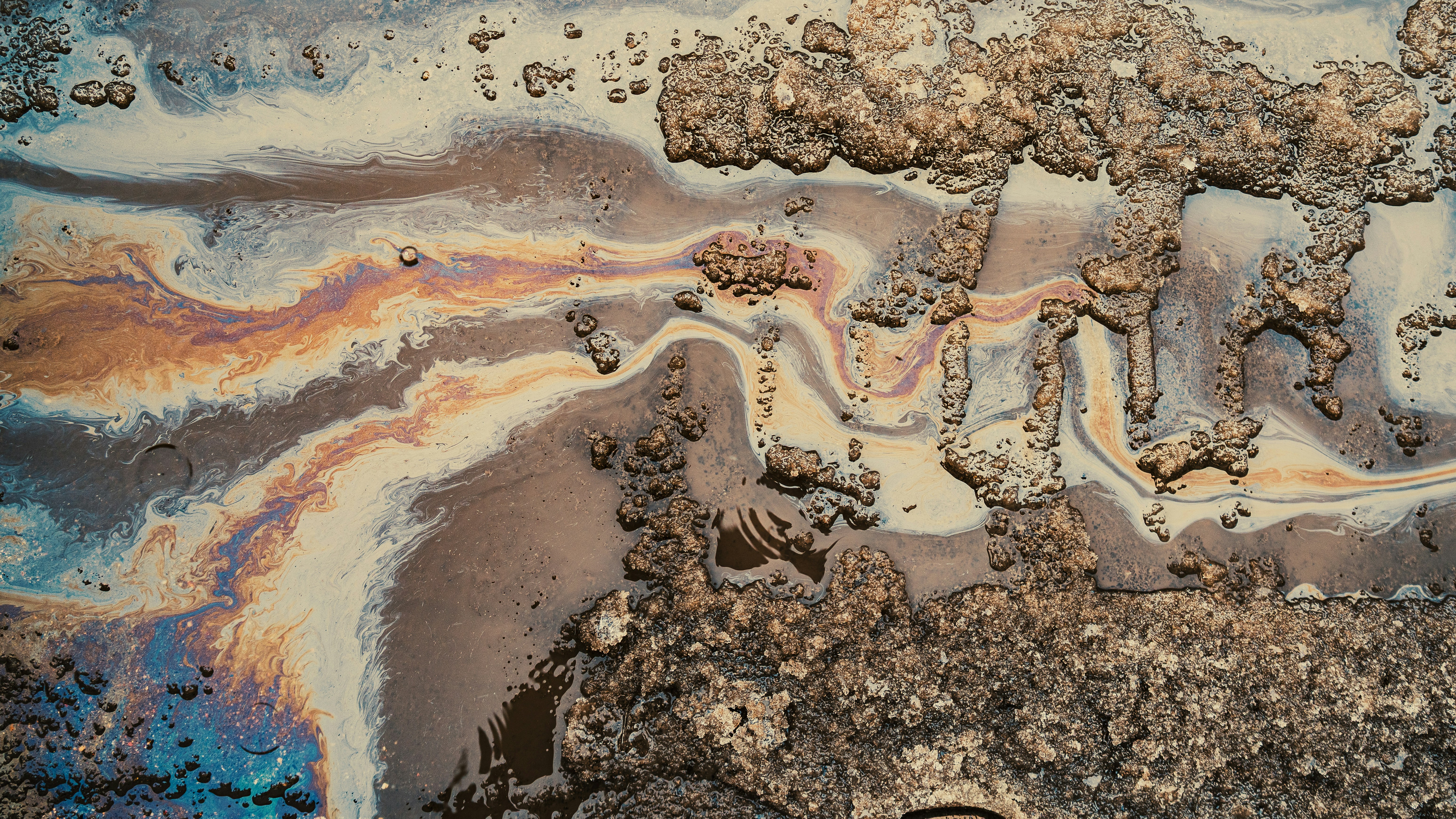 Iridescent oil slick on a textured, rocky surface