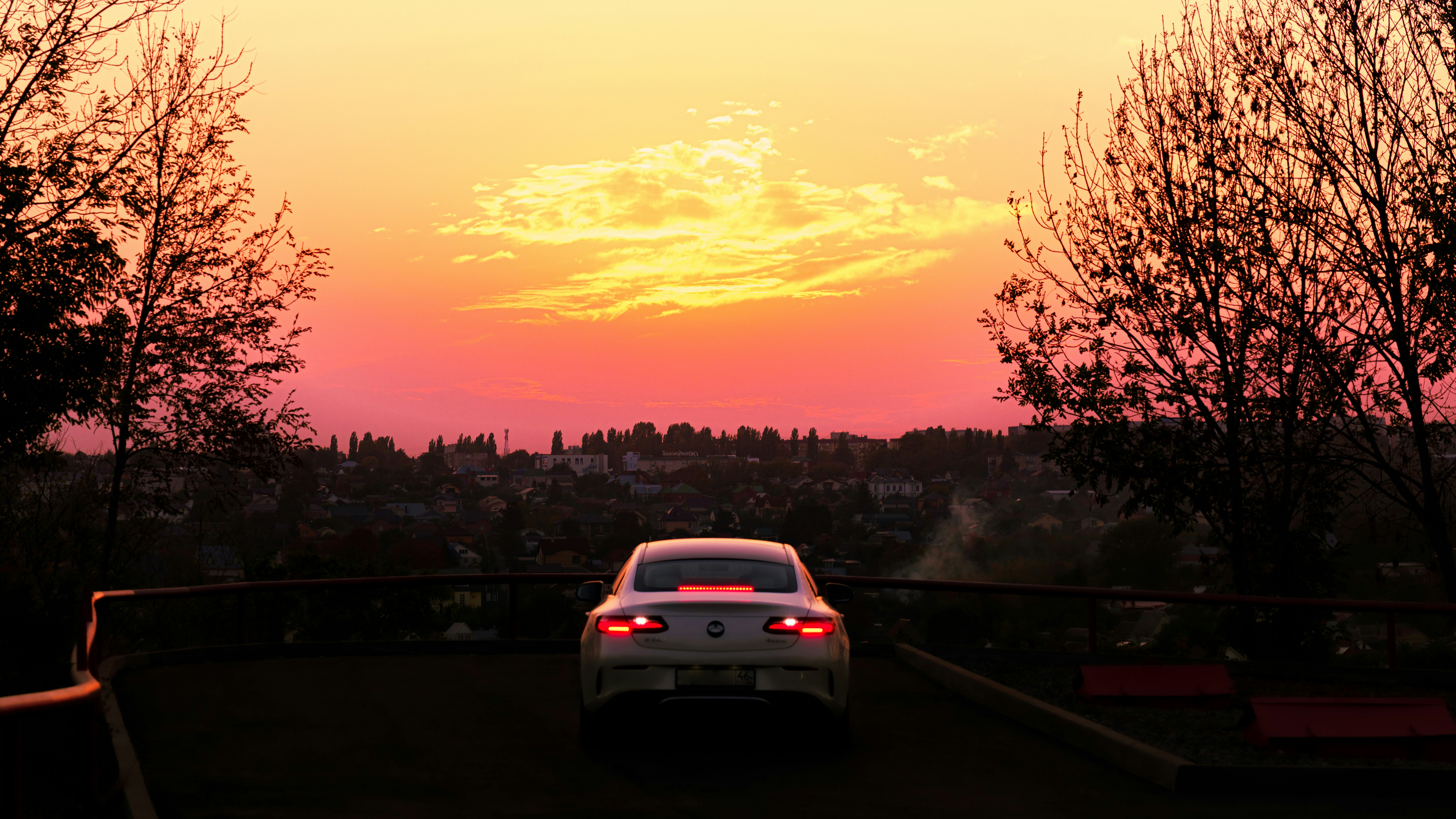Car driving towards a vibrant sunset sky.