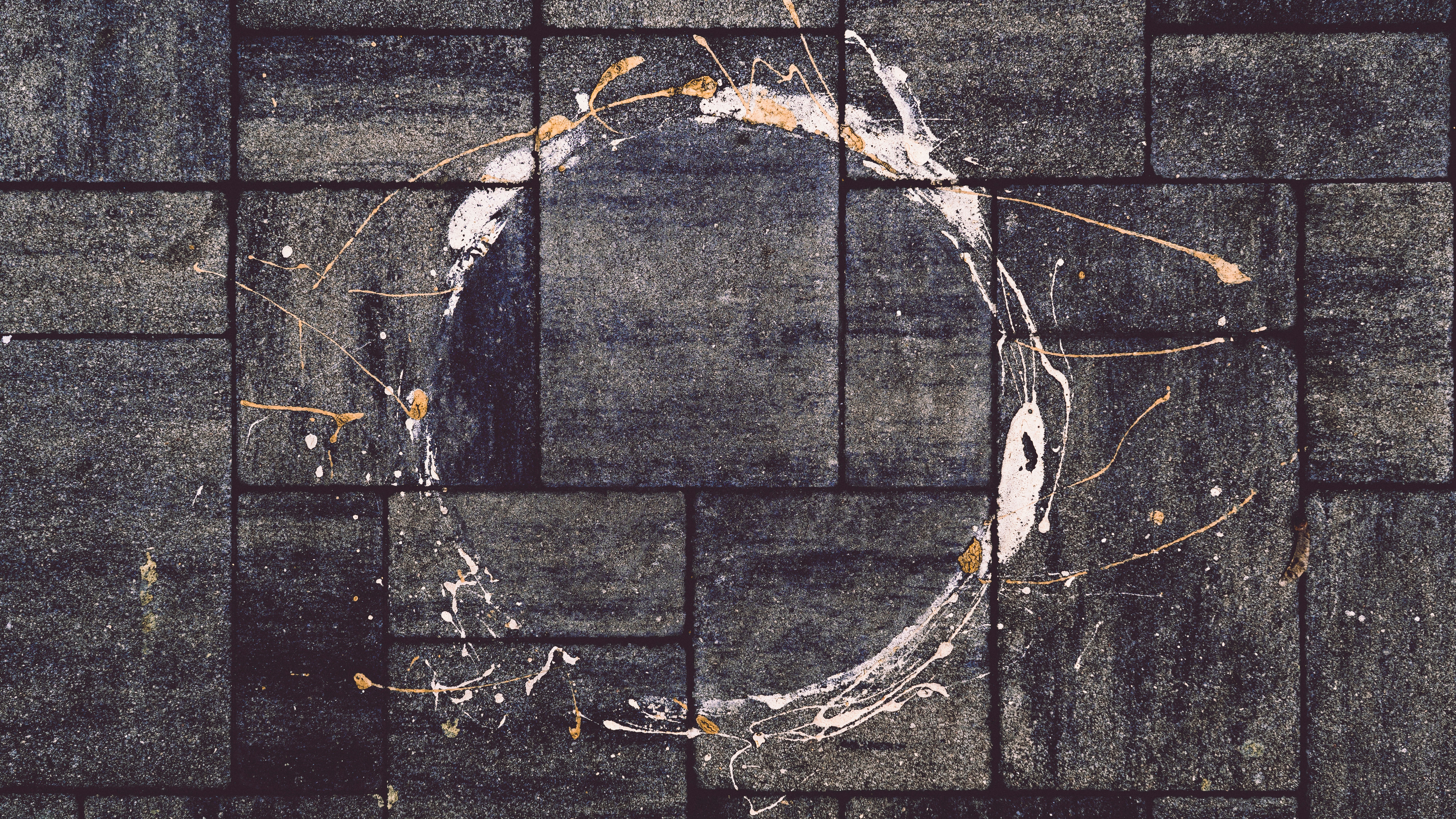 White paint splattered in a circle on dark tiles.