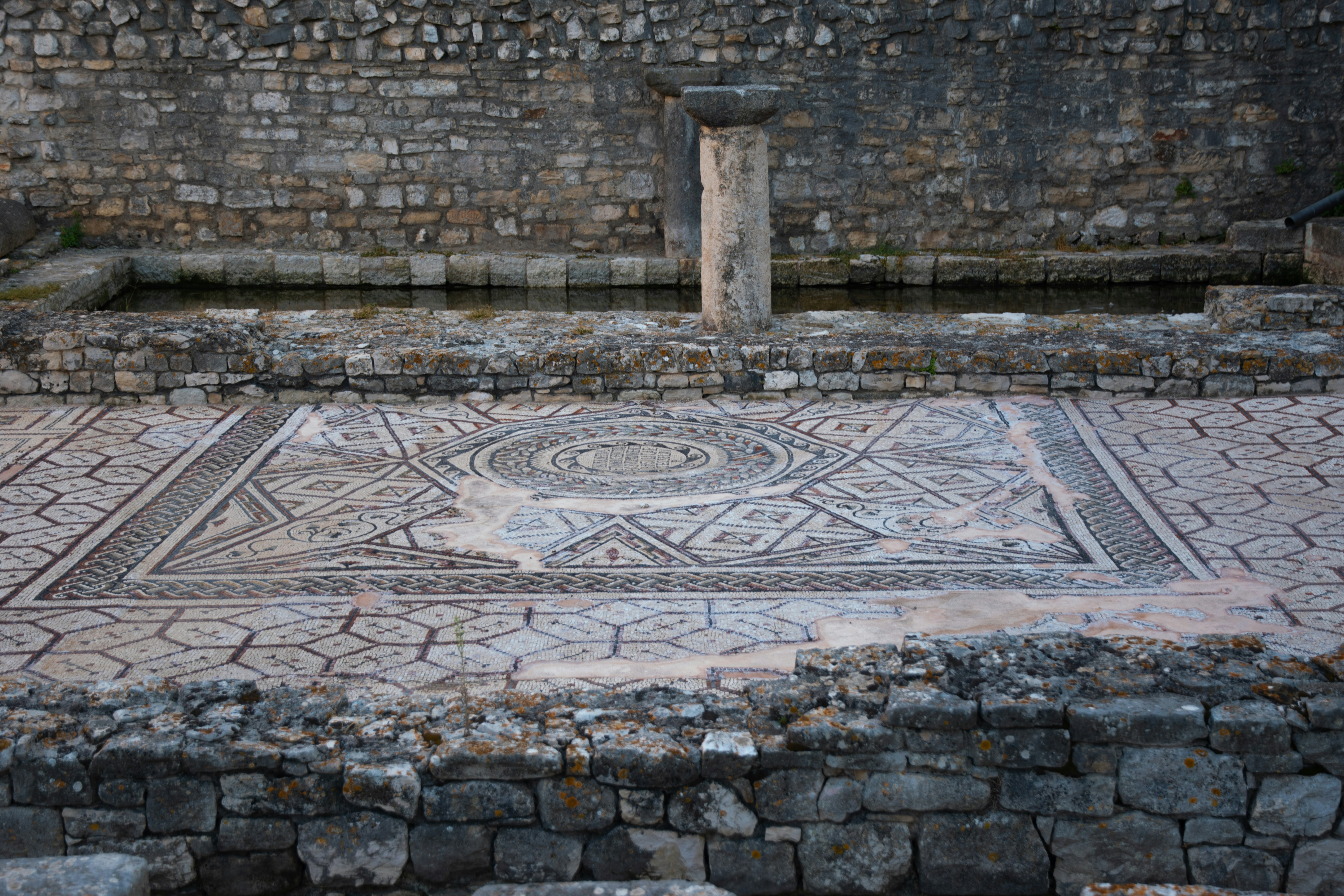 Ancient mosaic floor in stone ruins with column