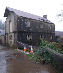 Dilapidated old house with broken windows and overgrown garden.