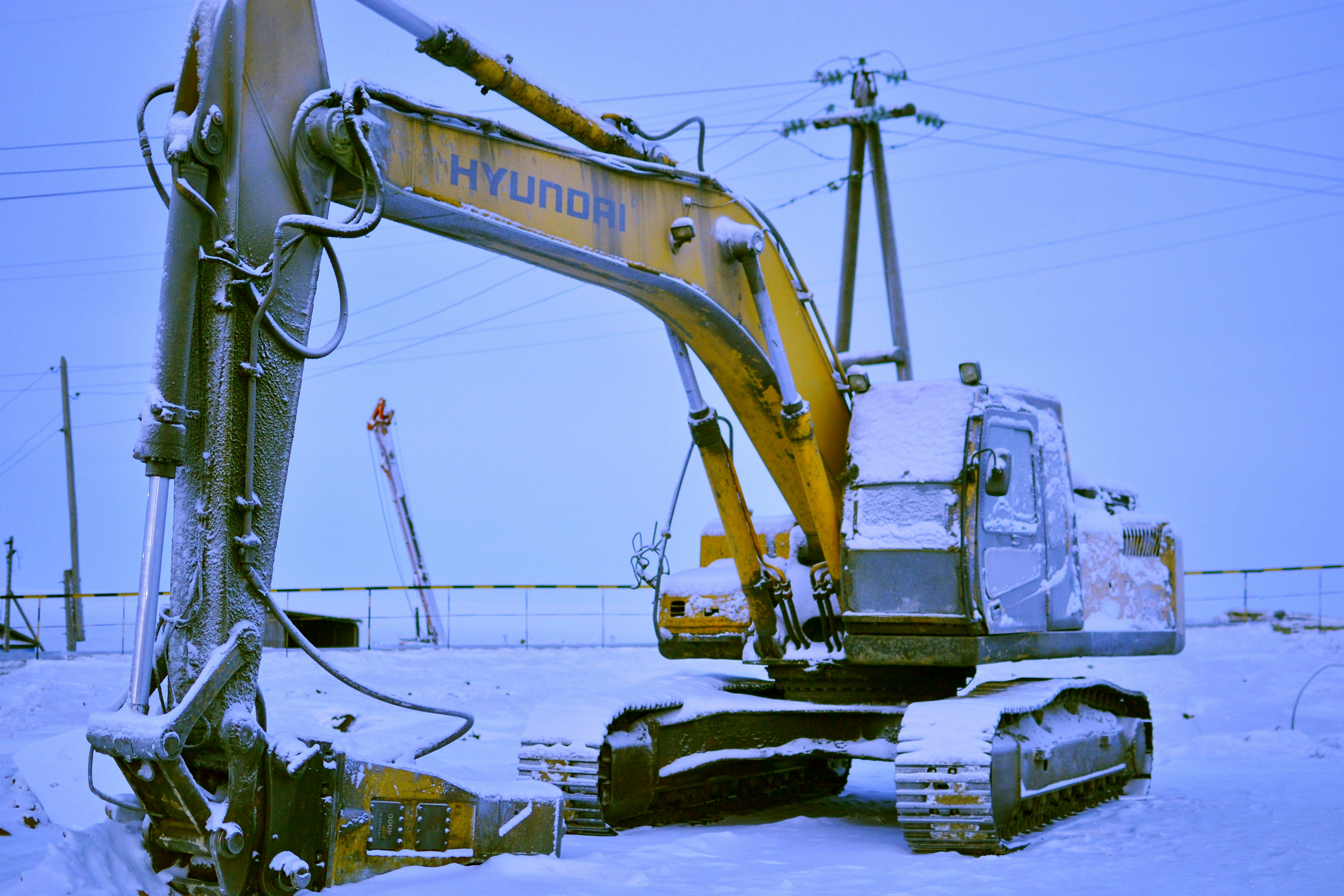 Yellow hyundai excavator covered in snow