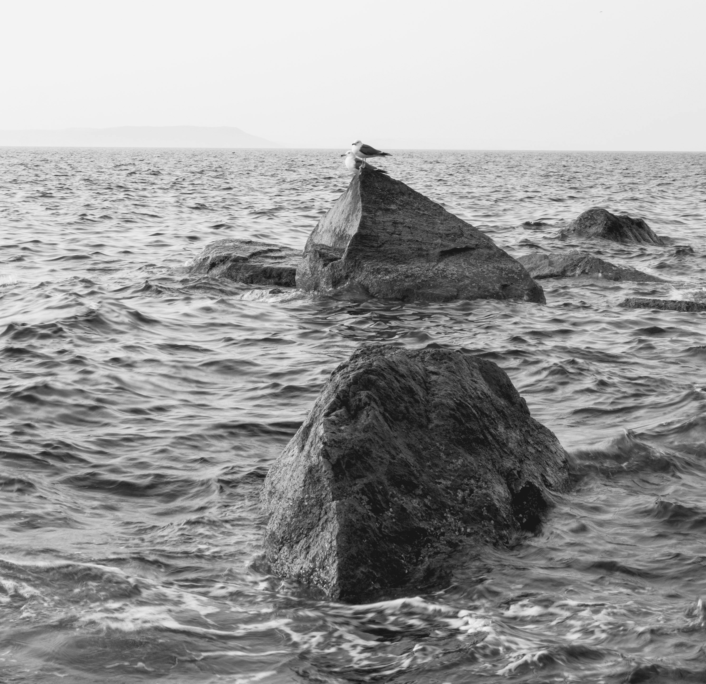 Large rocks emerge from the choppy ocean water.