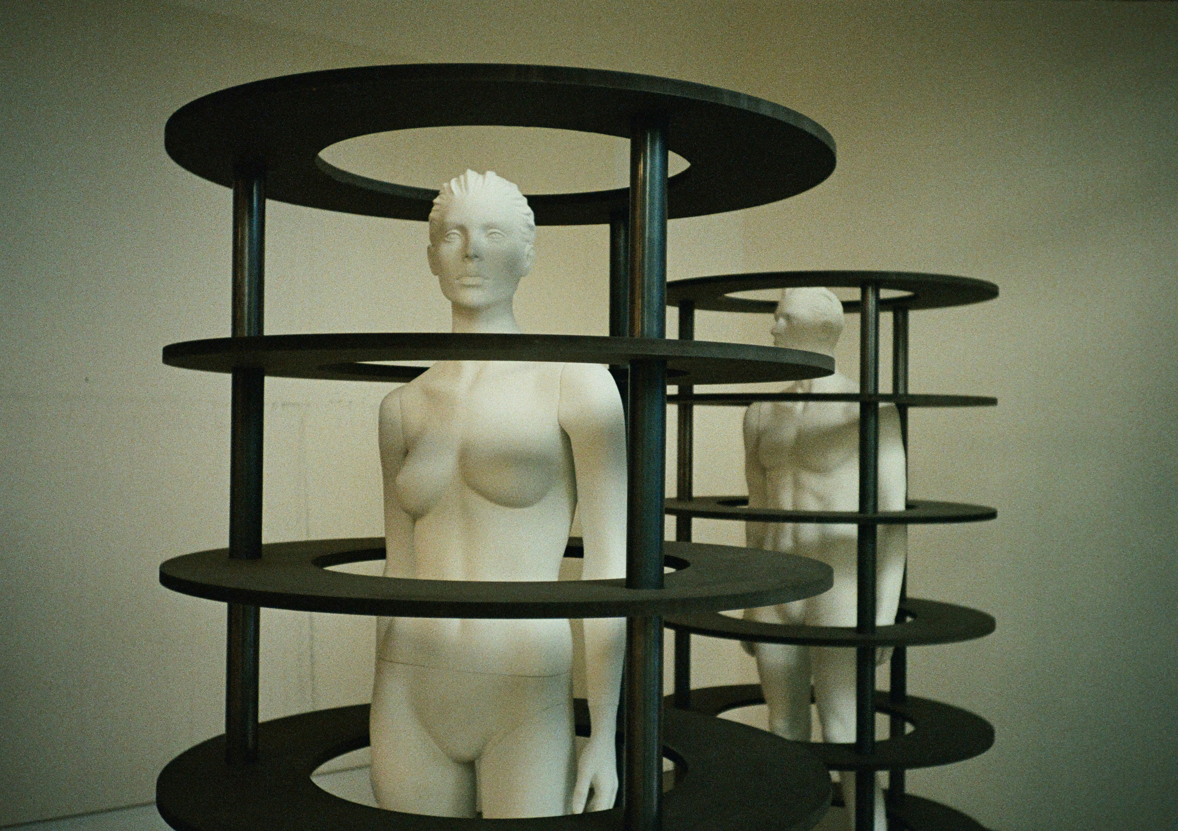 Two white mannequins inside black circular structures