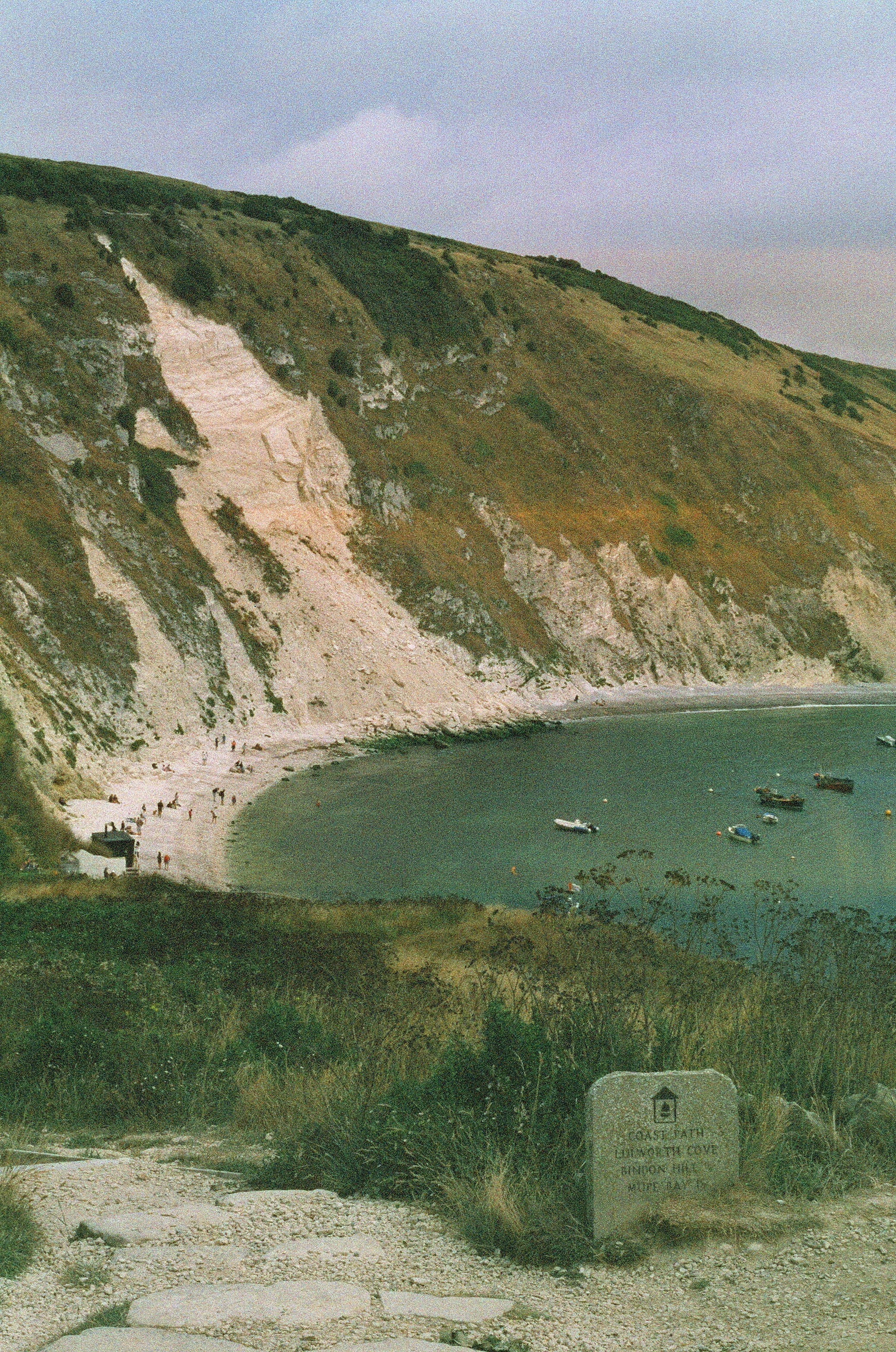 Boats anchored in a calm bay with a rocky coastline.