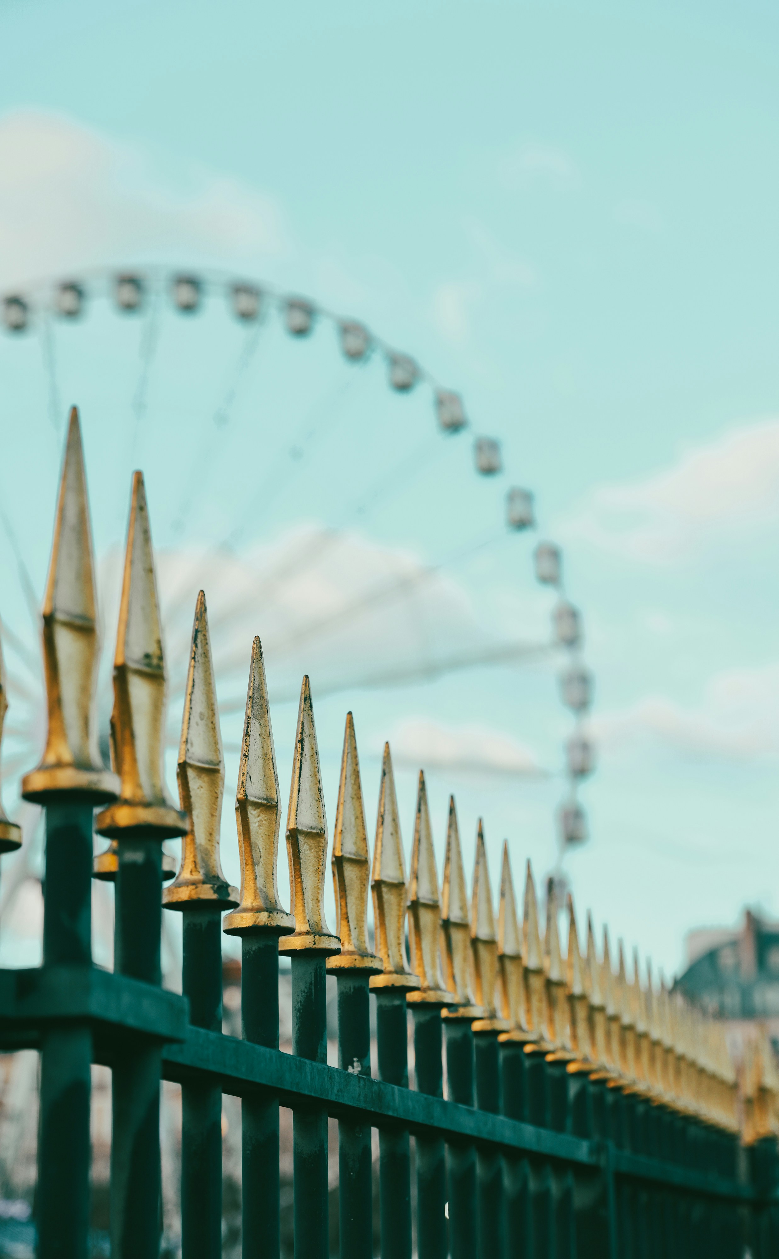 A ferris wheel behind a decorative metal fence.
