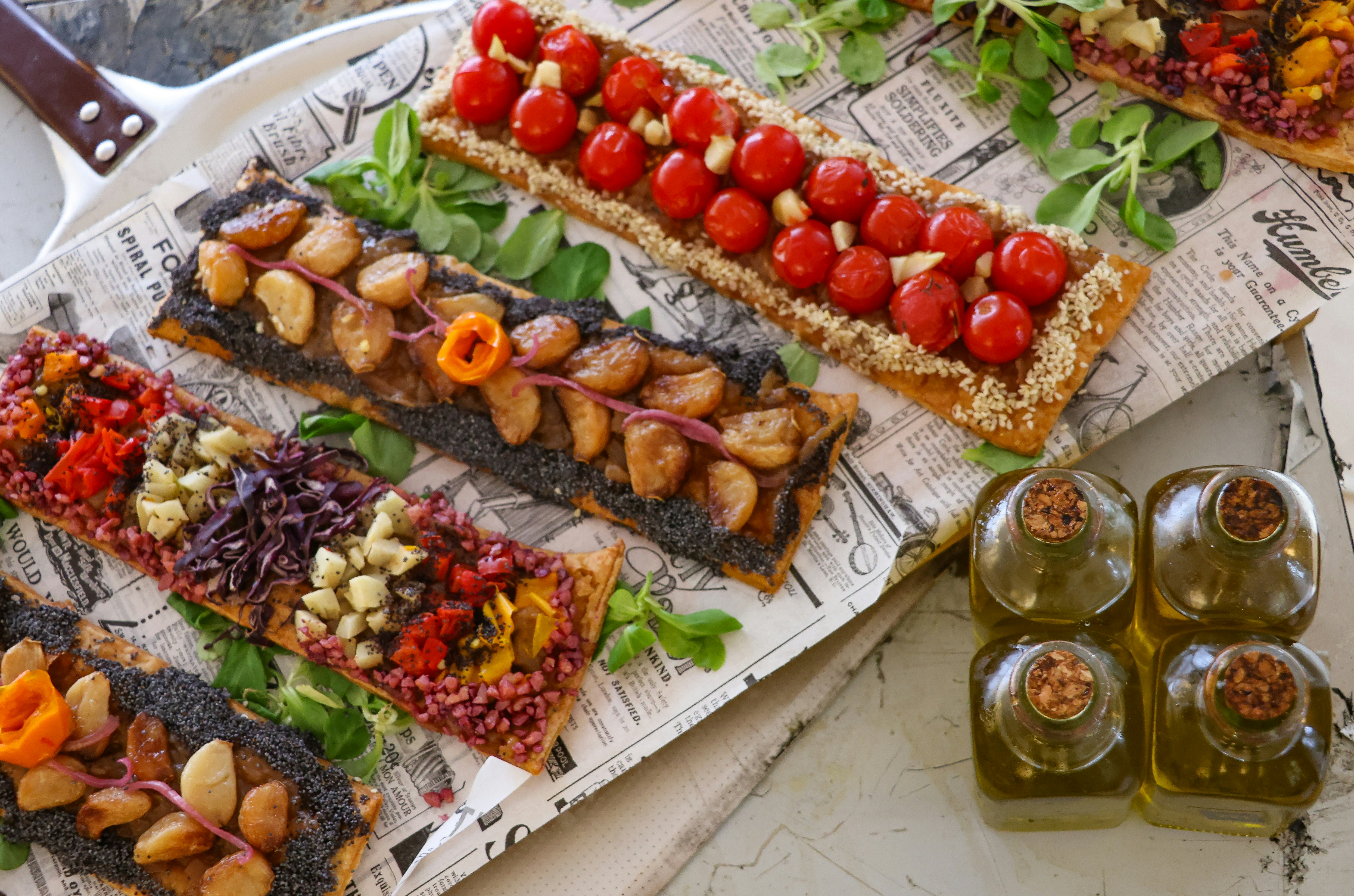 Four rectangular tarts with various toppings and olive oil.