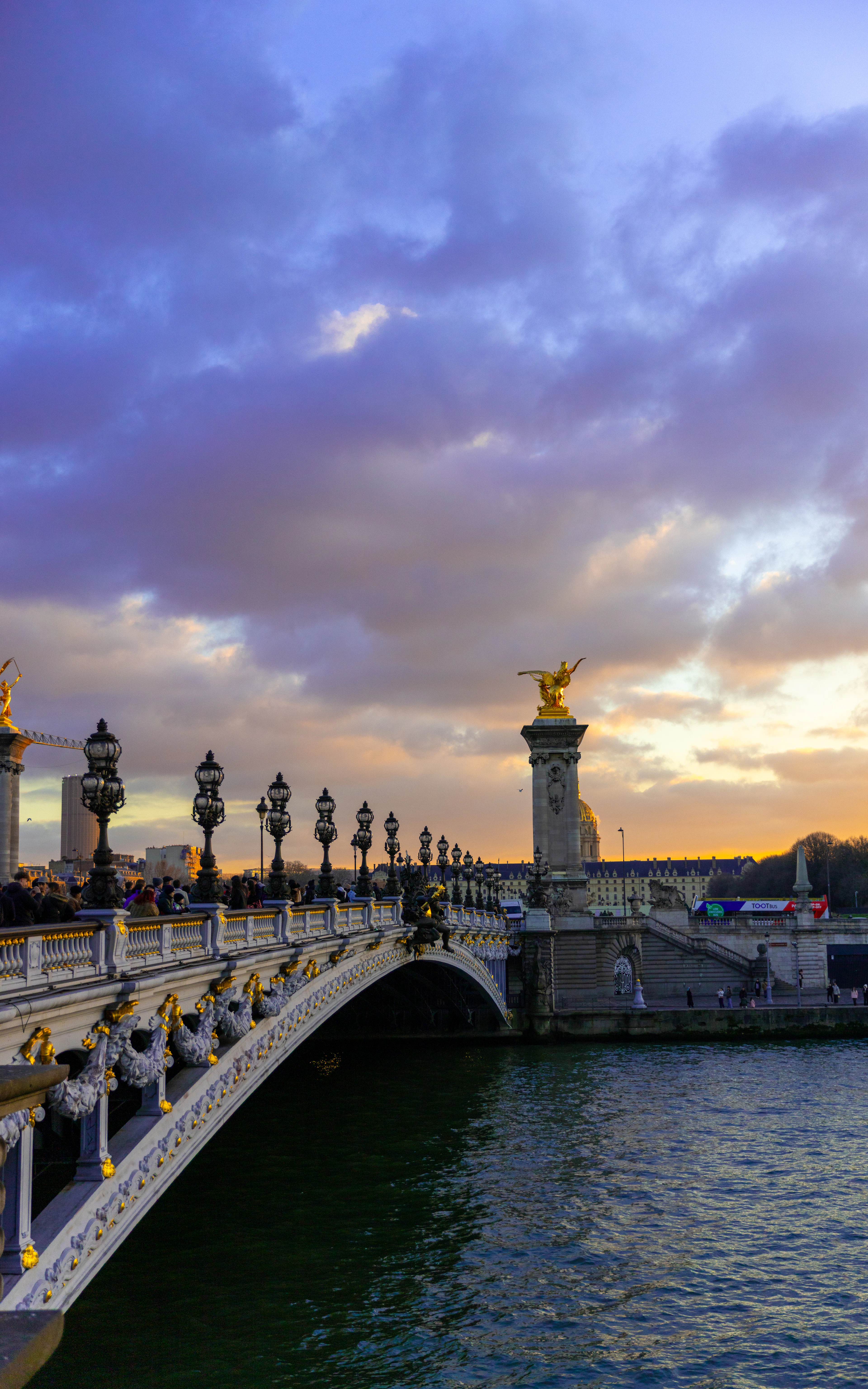 Ornate lamp posts and a gilded winged statue on the Pont Alexandre III over the Seine at sunset, Paris