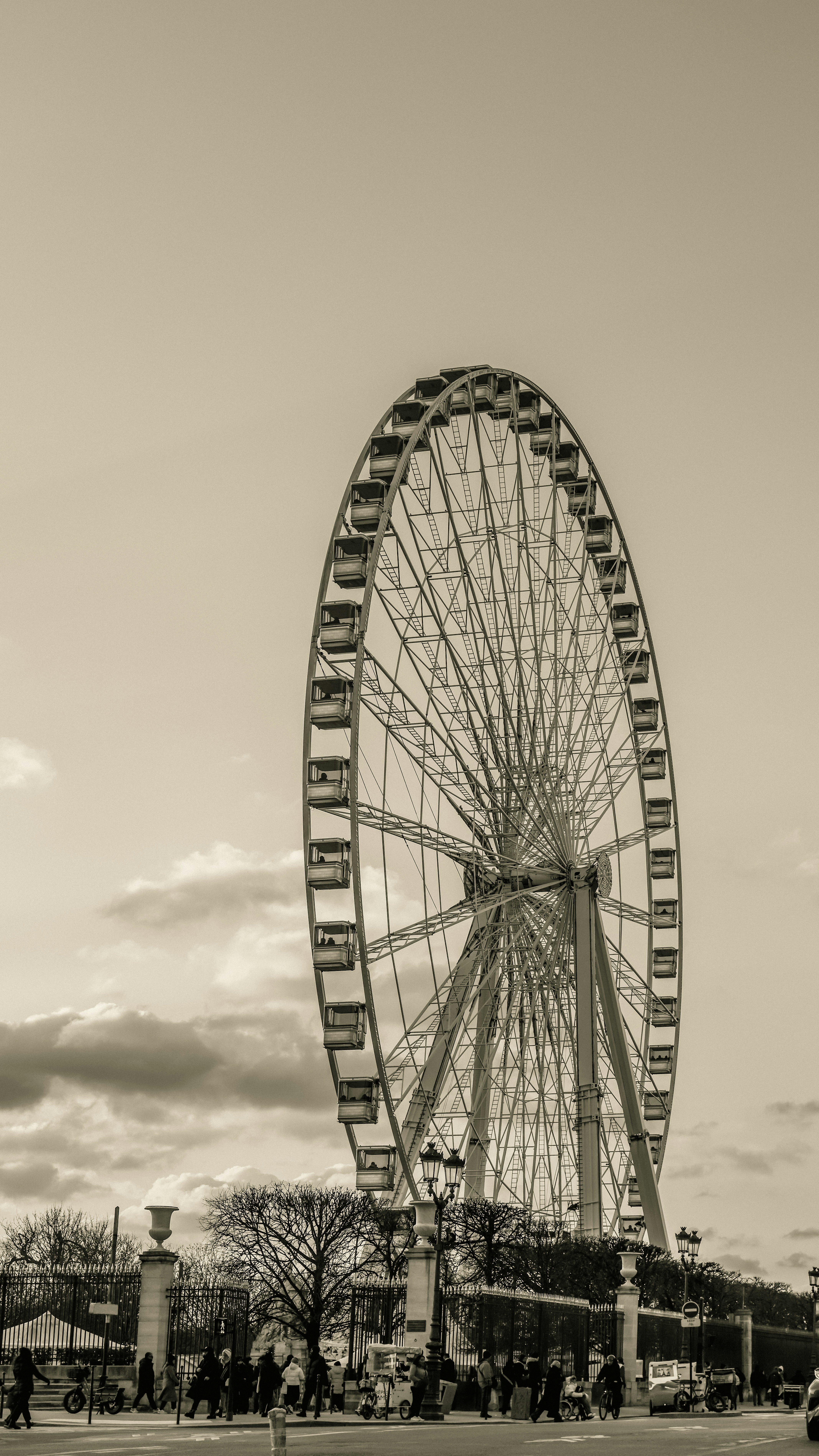 A large ferris wheel stands against a cloudy sky.