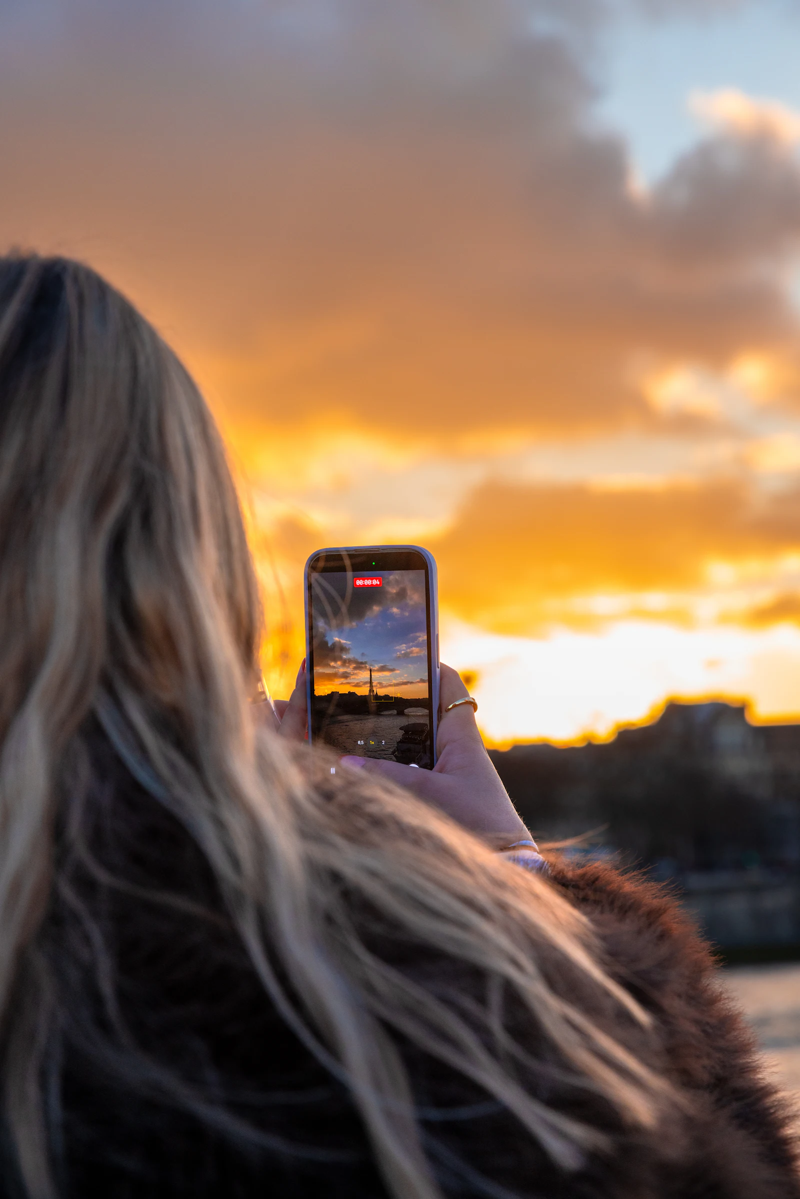 Traveller recording a golden sunset over a European city on her phone, a good moment to check travel data usage