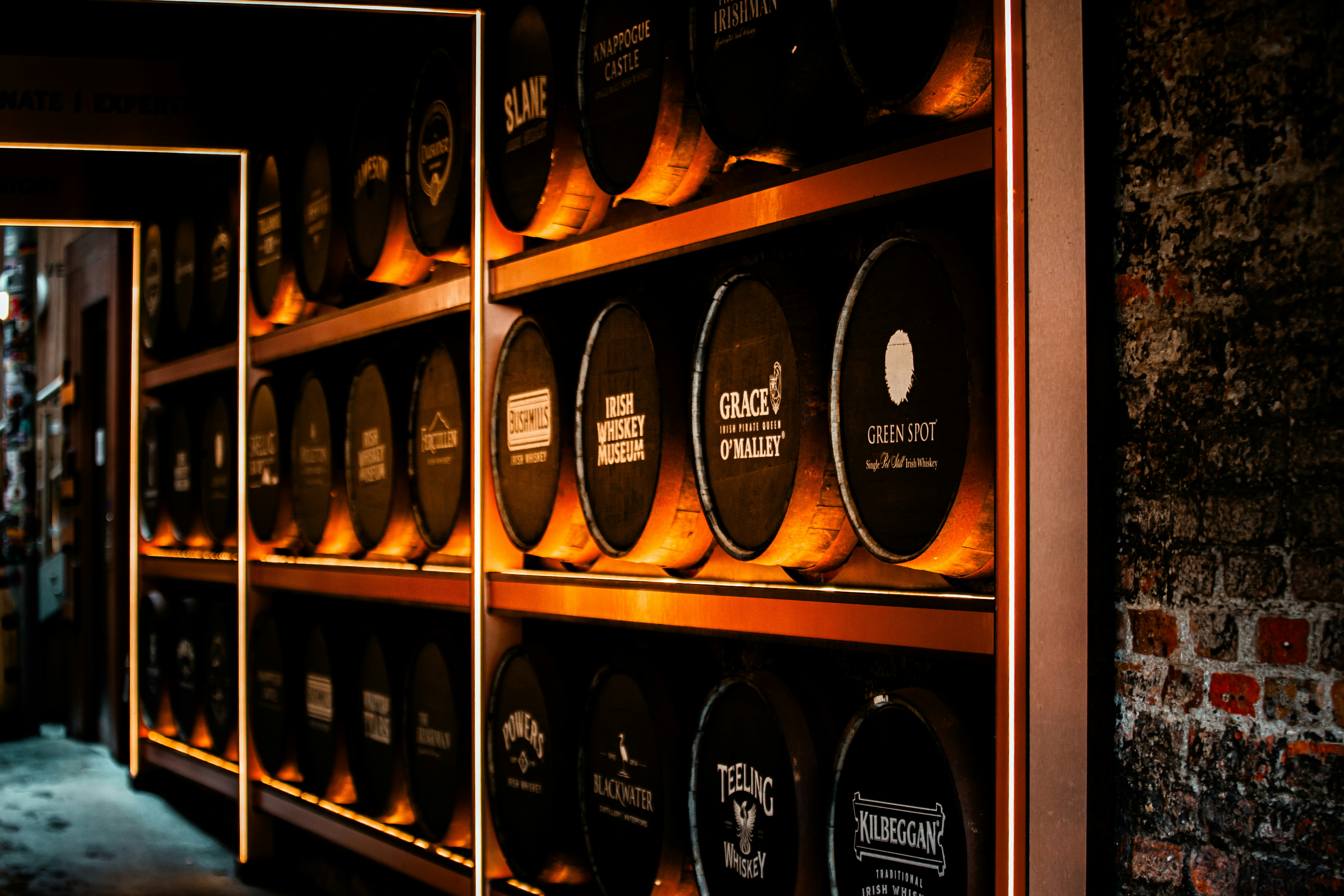 Rows of whiskey barrels stacked on shelves in a cellar.