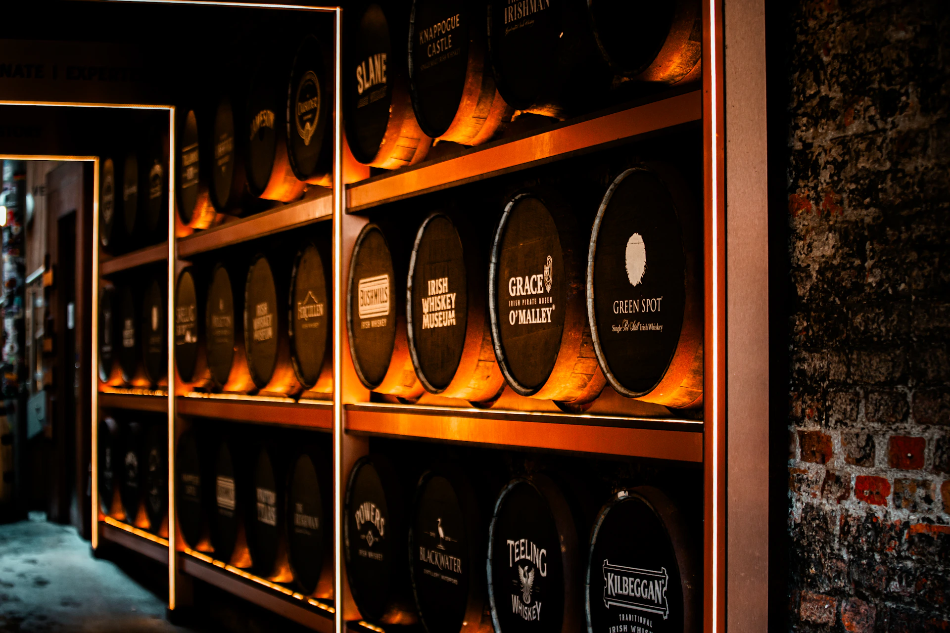 Rows of whiskey barrels stacked on shelves in a cellar.