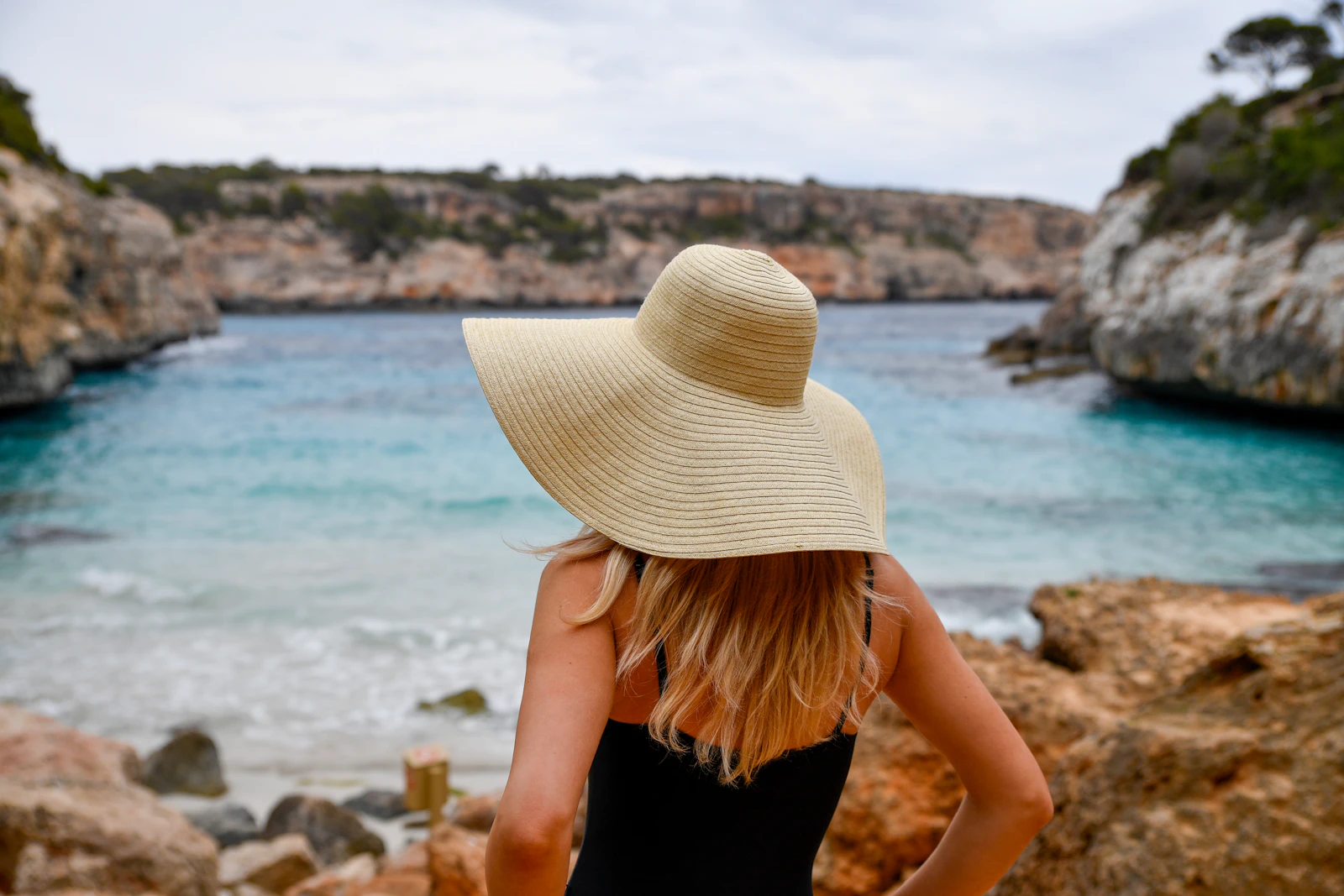 woman in a sun hat looking out at a tranquil bay