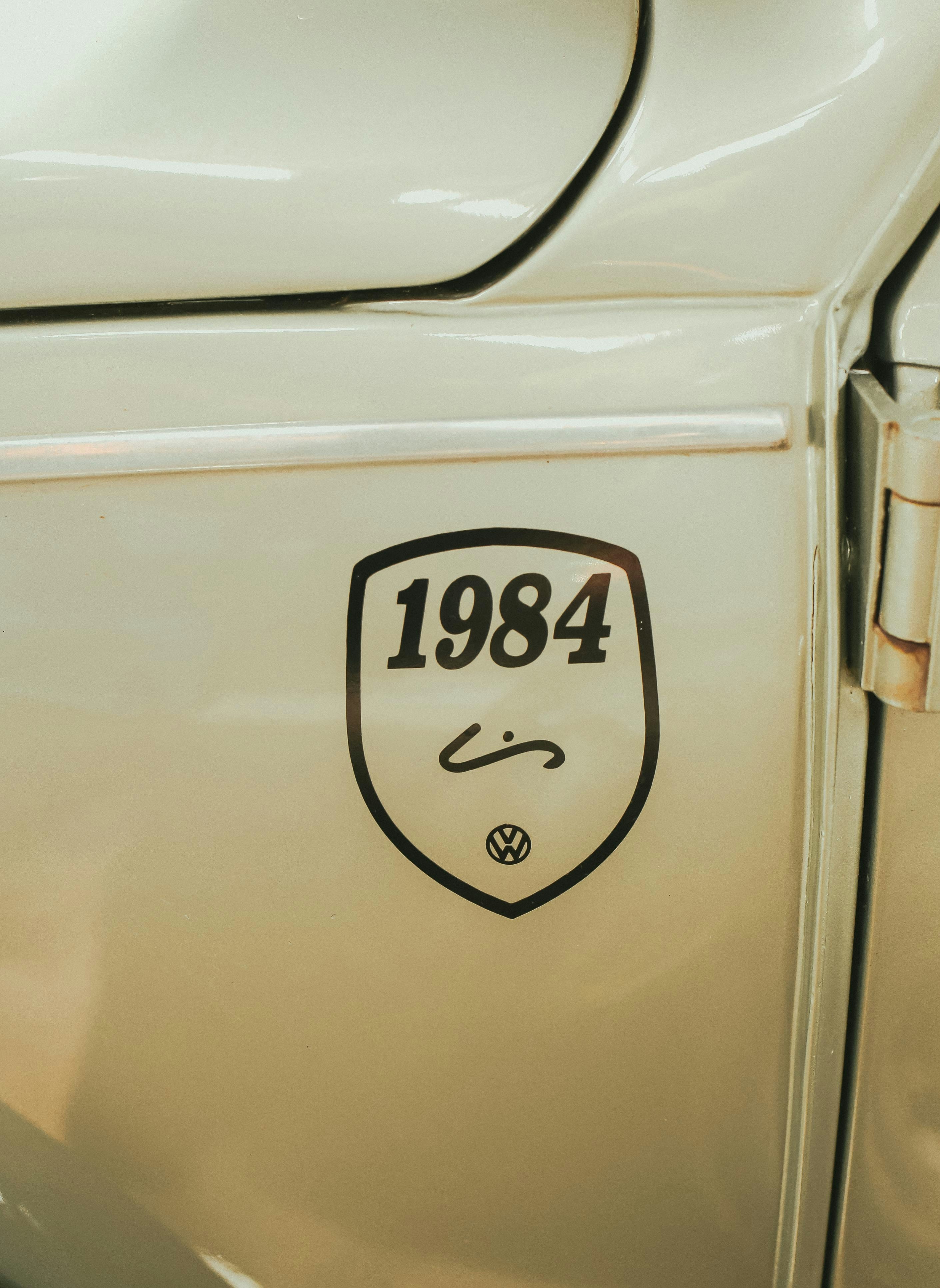 Close-up of a 1984 emblem on a white car.