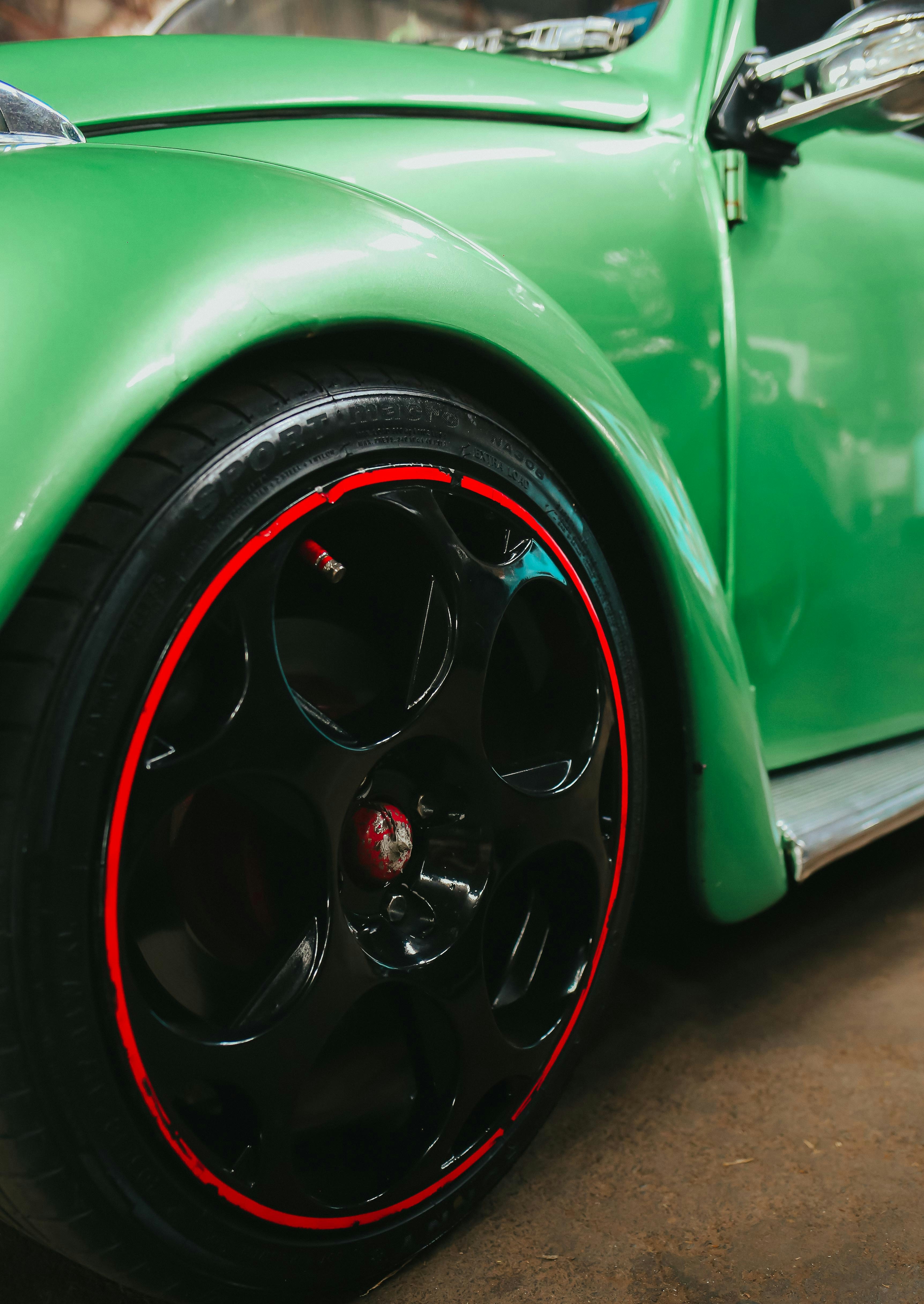 Close-up of a vintage green car with black wheels.