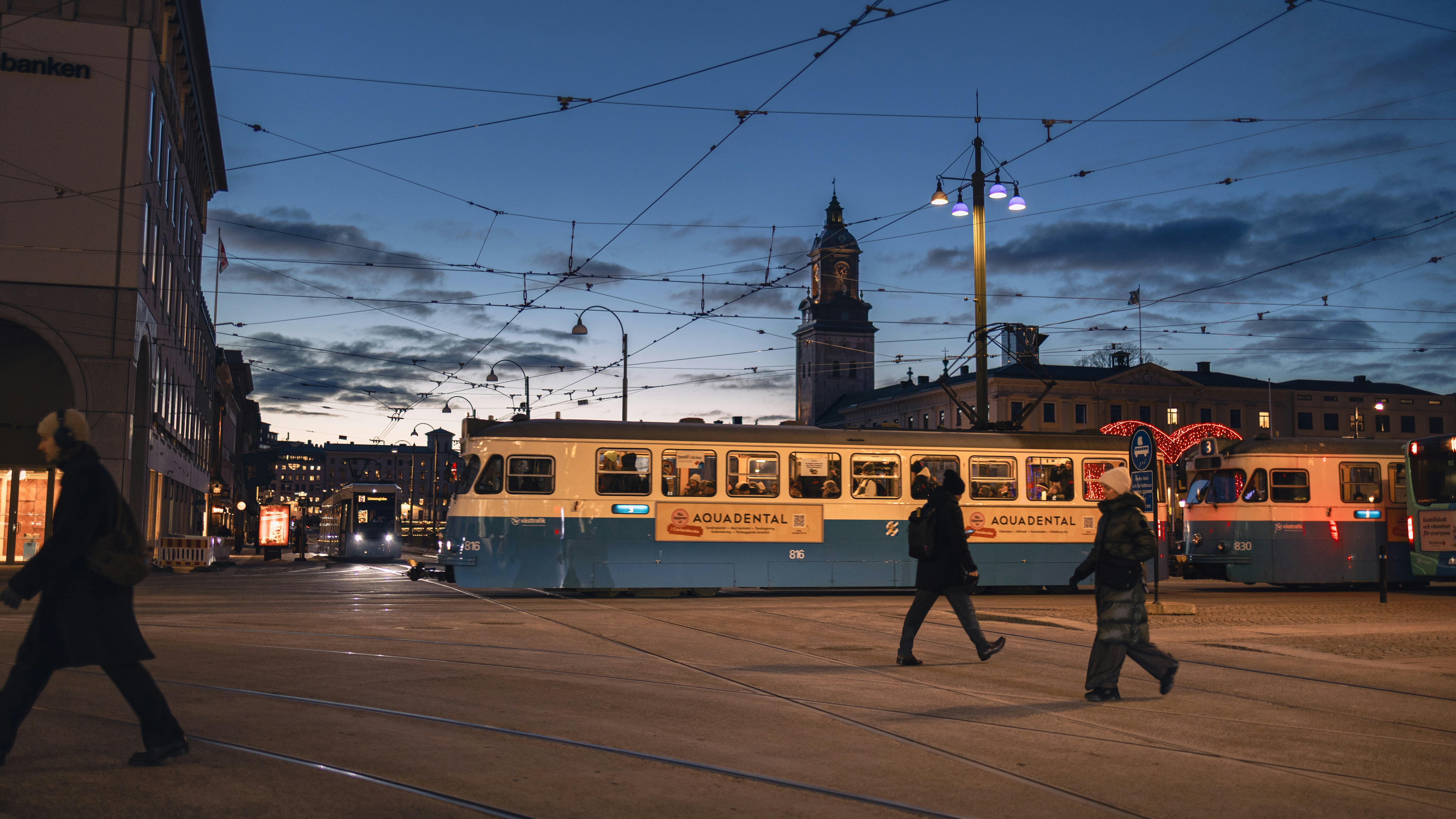 People crossing street near tram at dusk