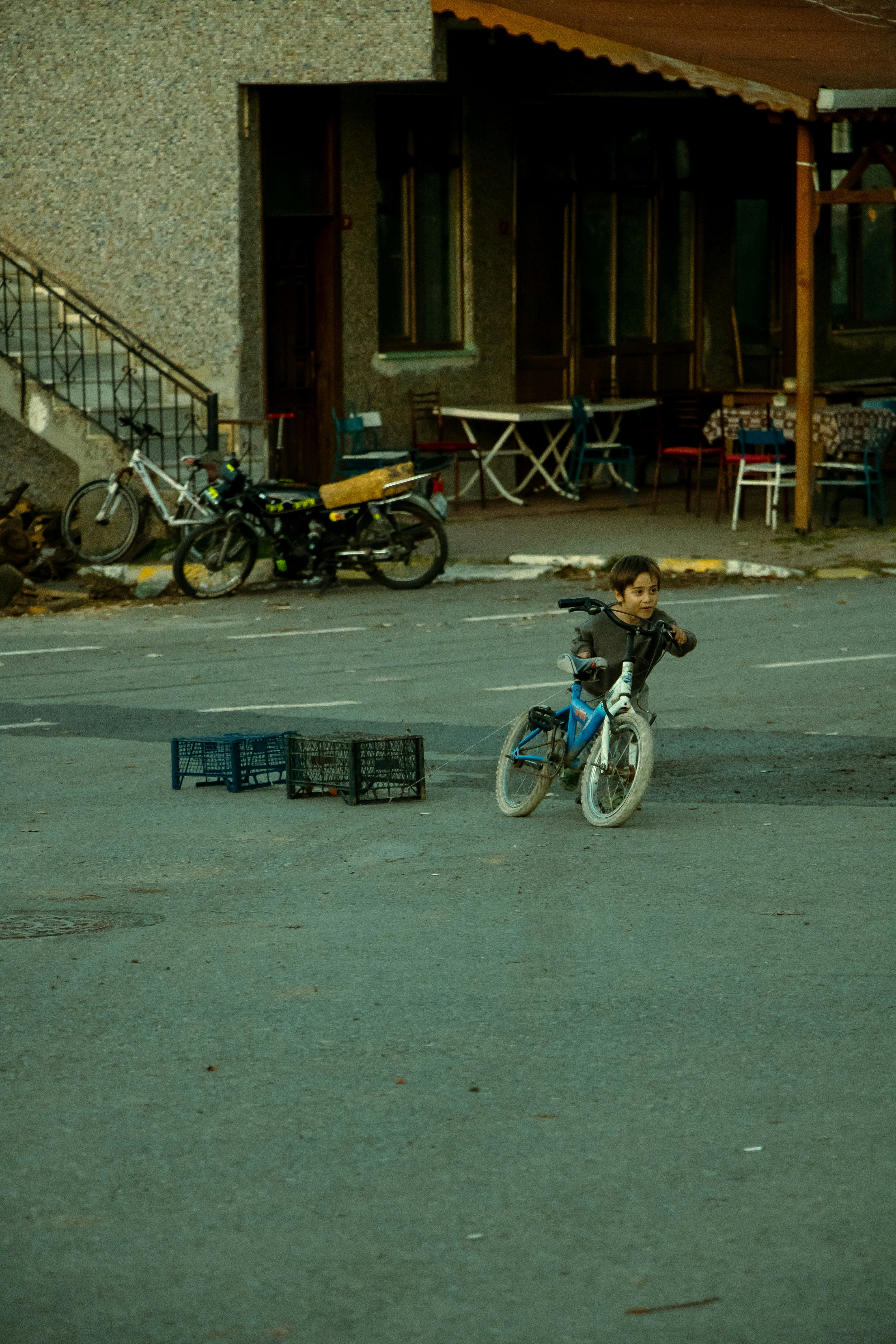 少年が自転車で通りの木箱の前を通り過ぎる
