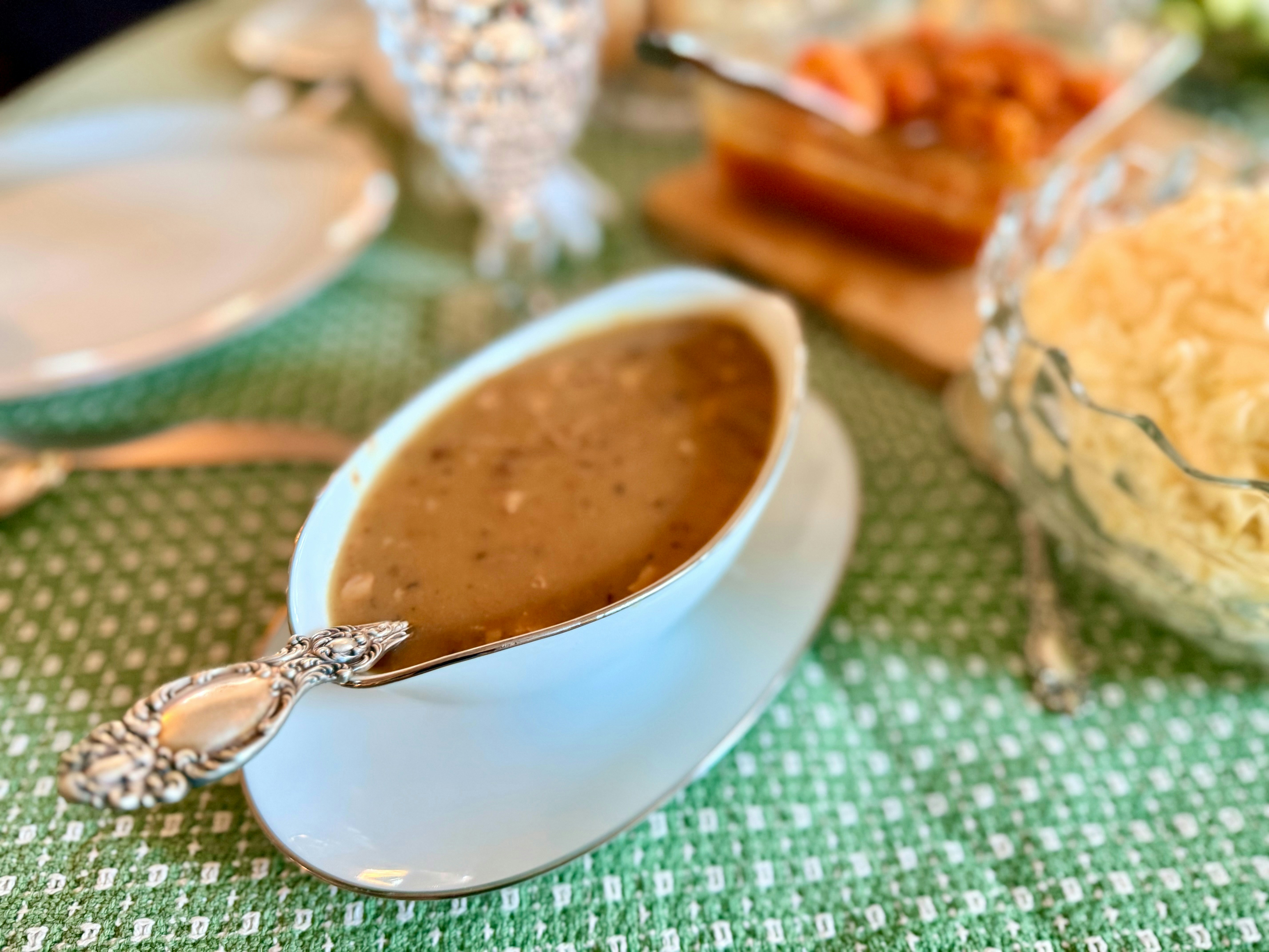 A gravy boat filled with brown gravy on a table.