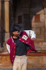 Young man in a varsity jacket adjusts clothing