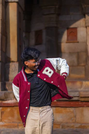 Young man in a varsity jacket adjusts clothing
