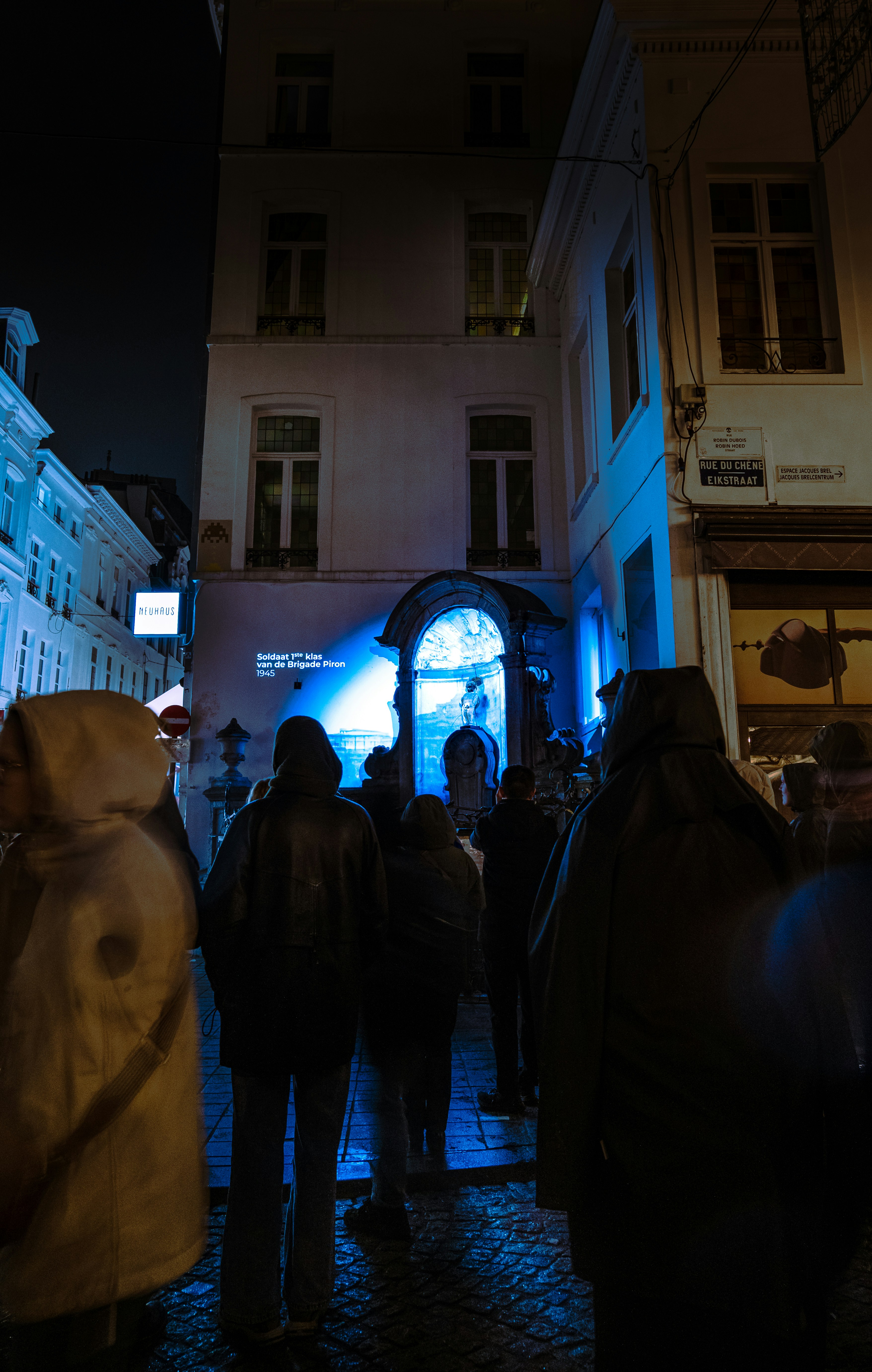 People gathered at night watching a blue light installation