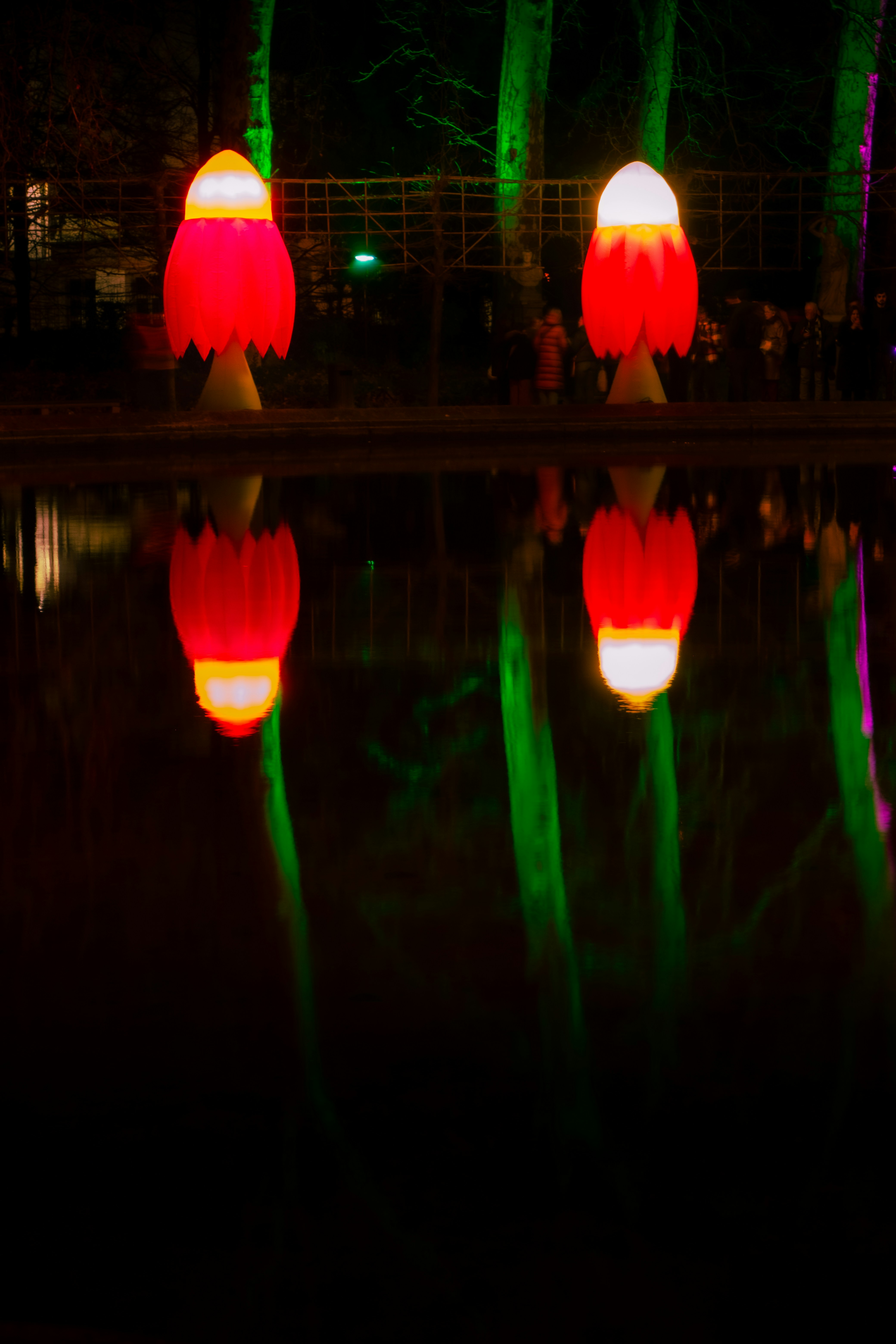 Two red mushroom lights reflected in water at night