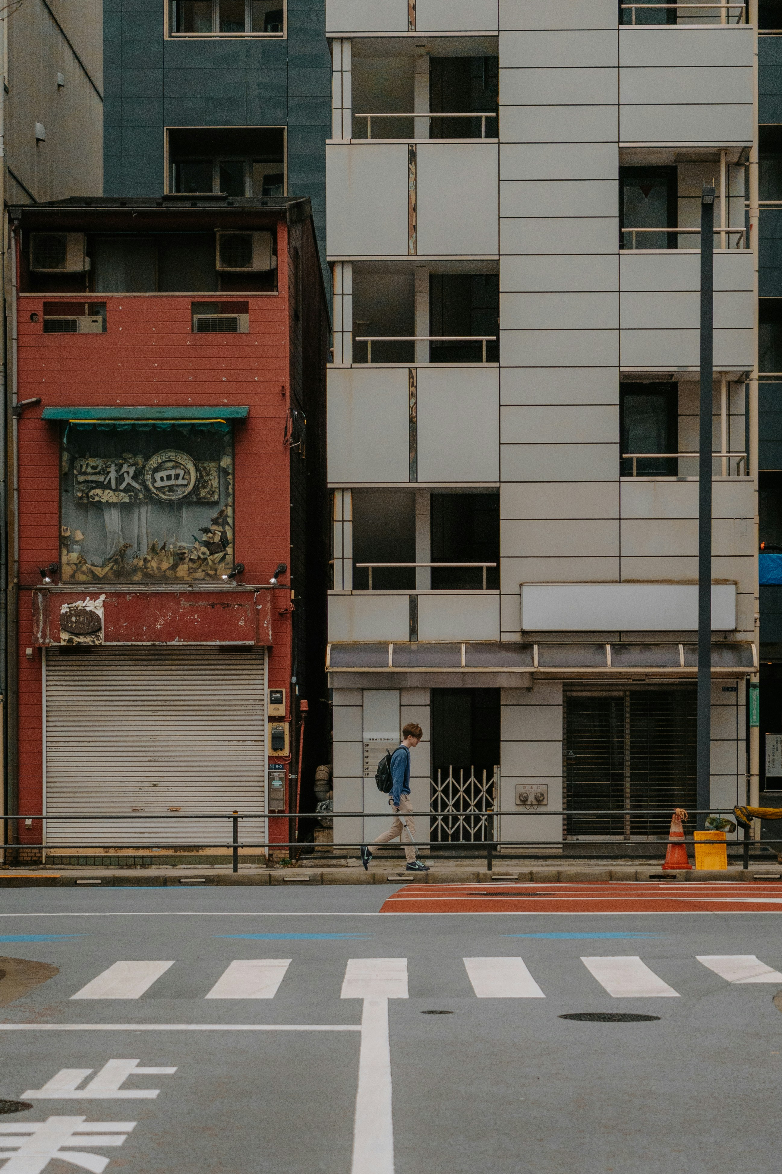 A person walks past buildings on a city street.