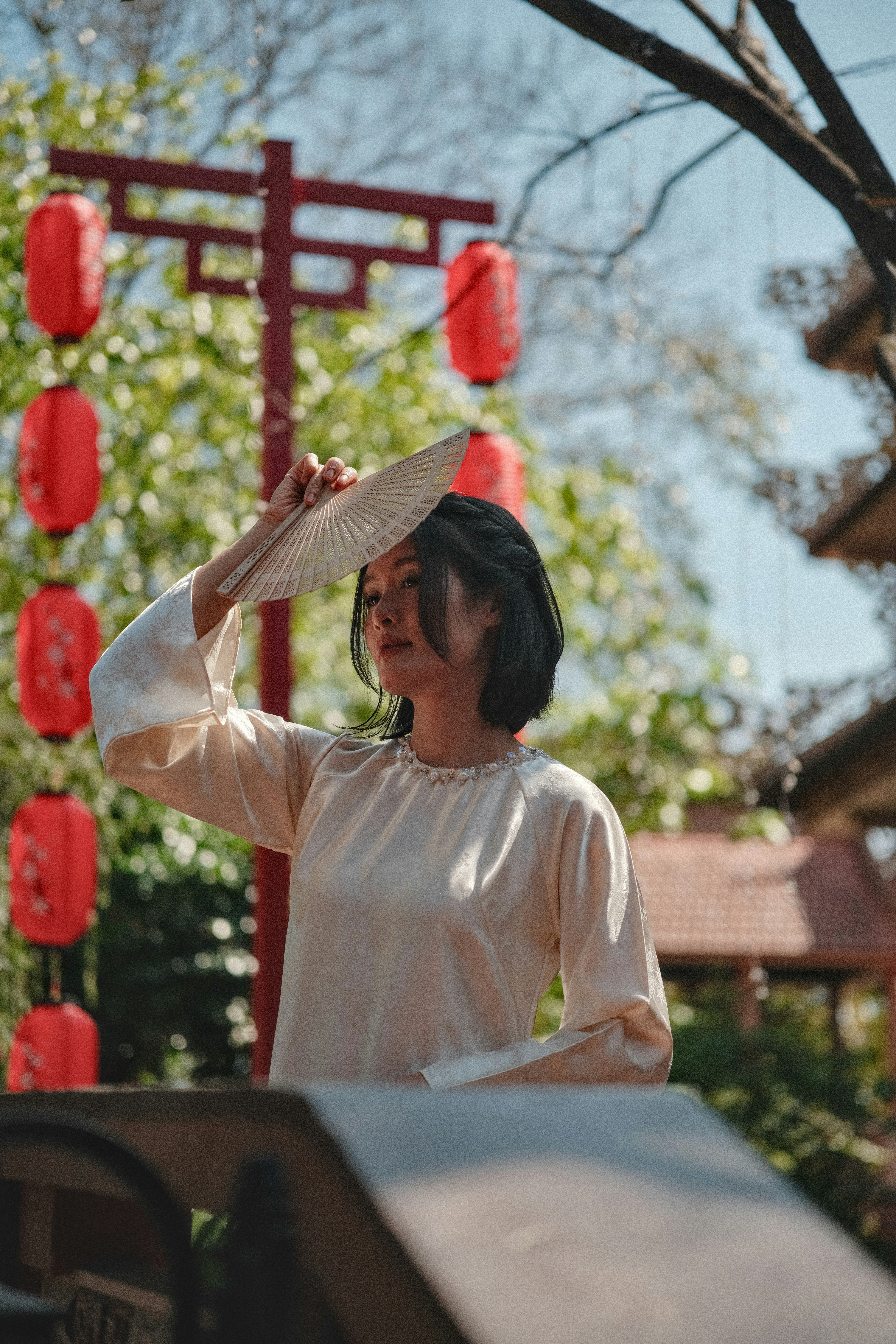 Woman in traditional dress holding a fan outdoors