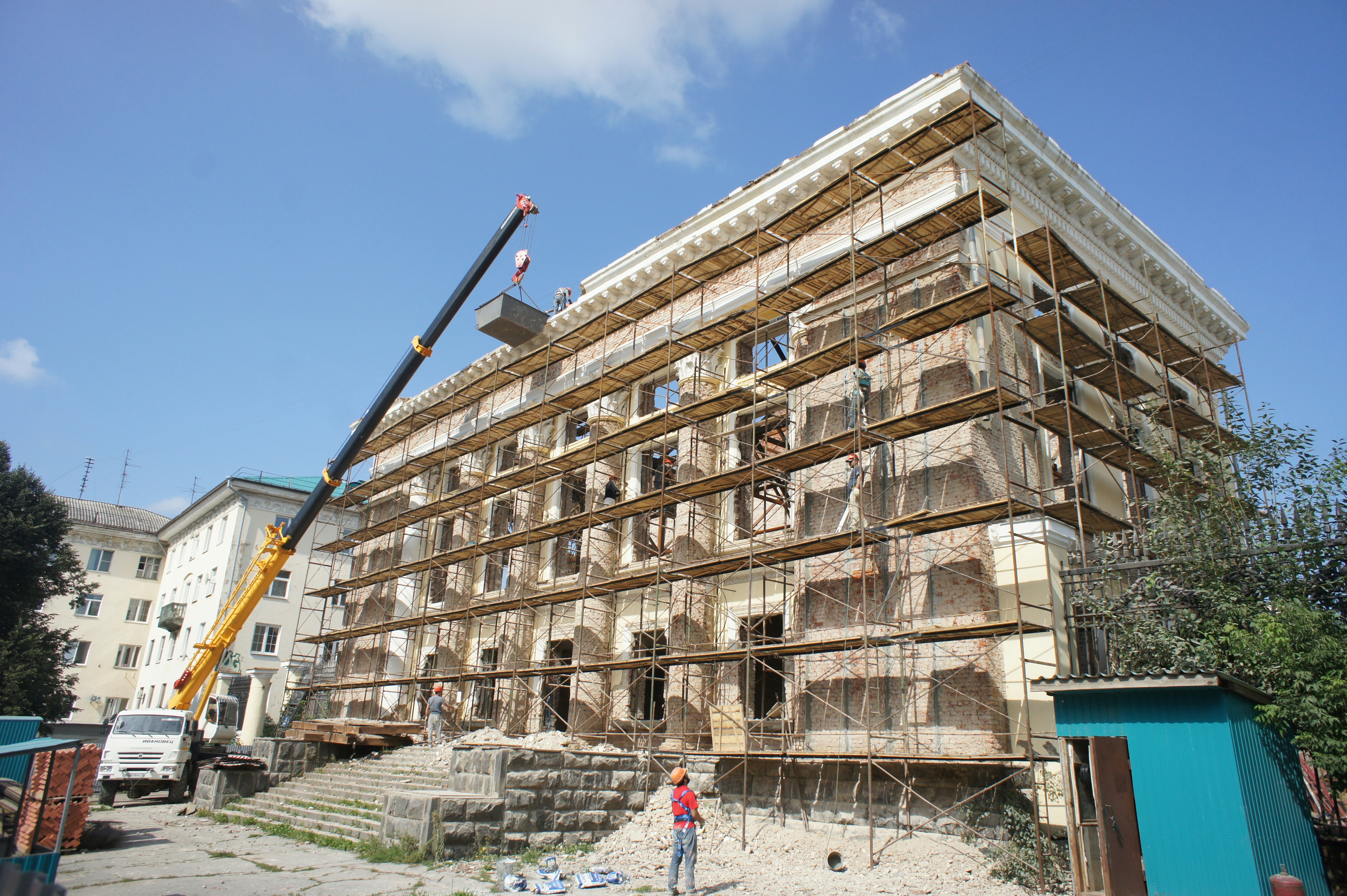 Building undergoing renovation with scaffolding and crane.