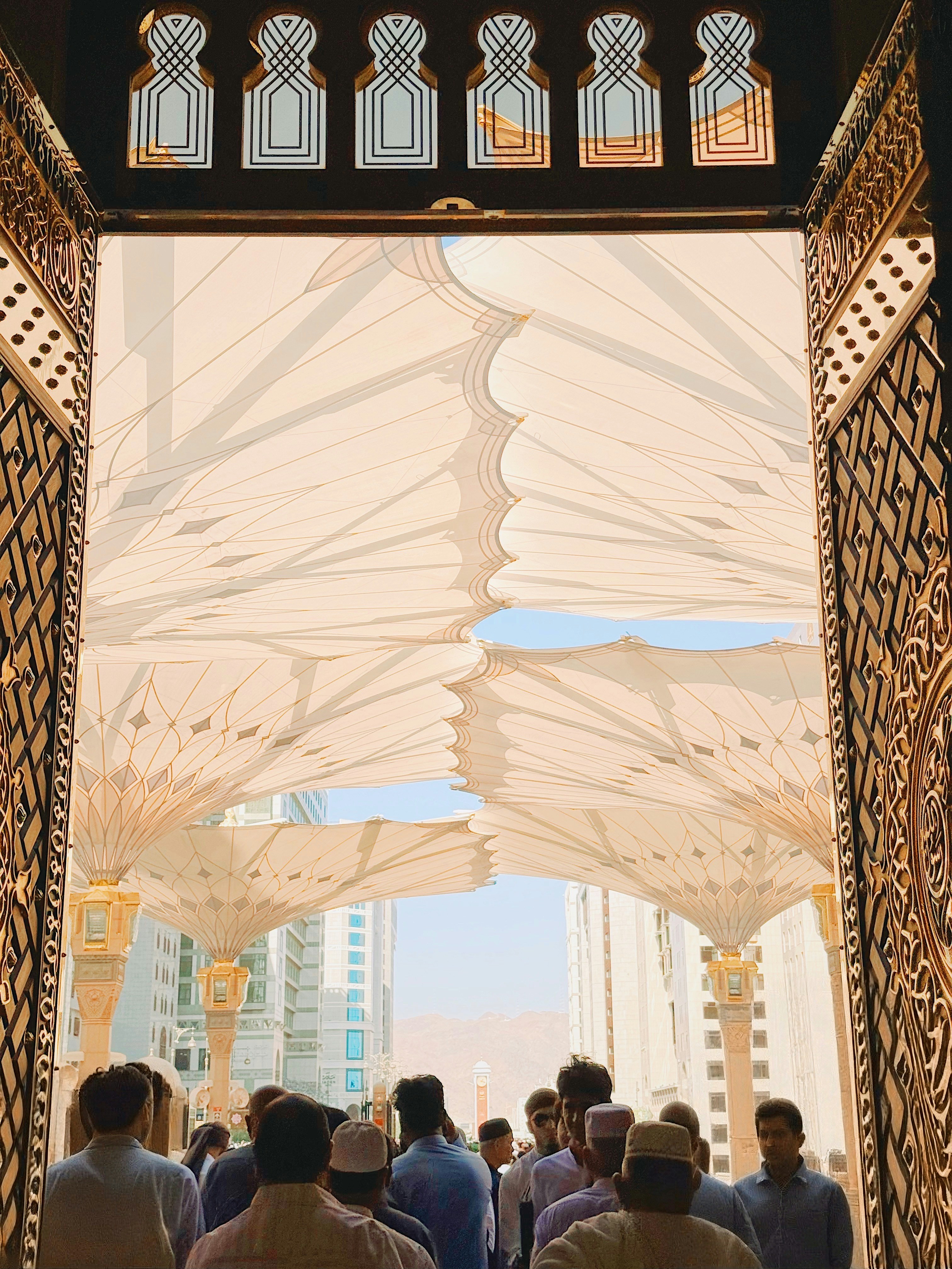 Persone che attraversano la porta ornata verso grandi ombrelli bianchi