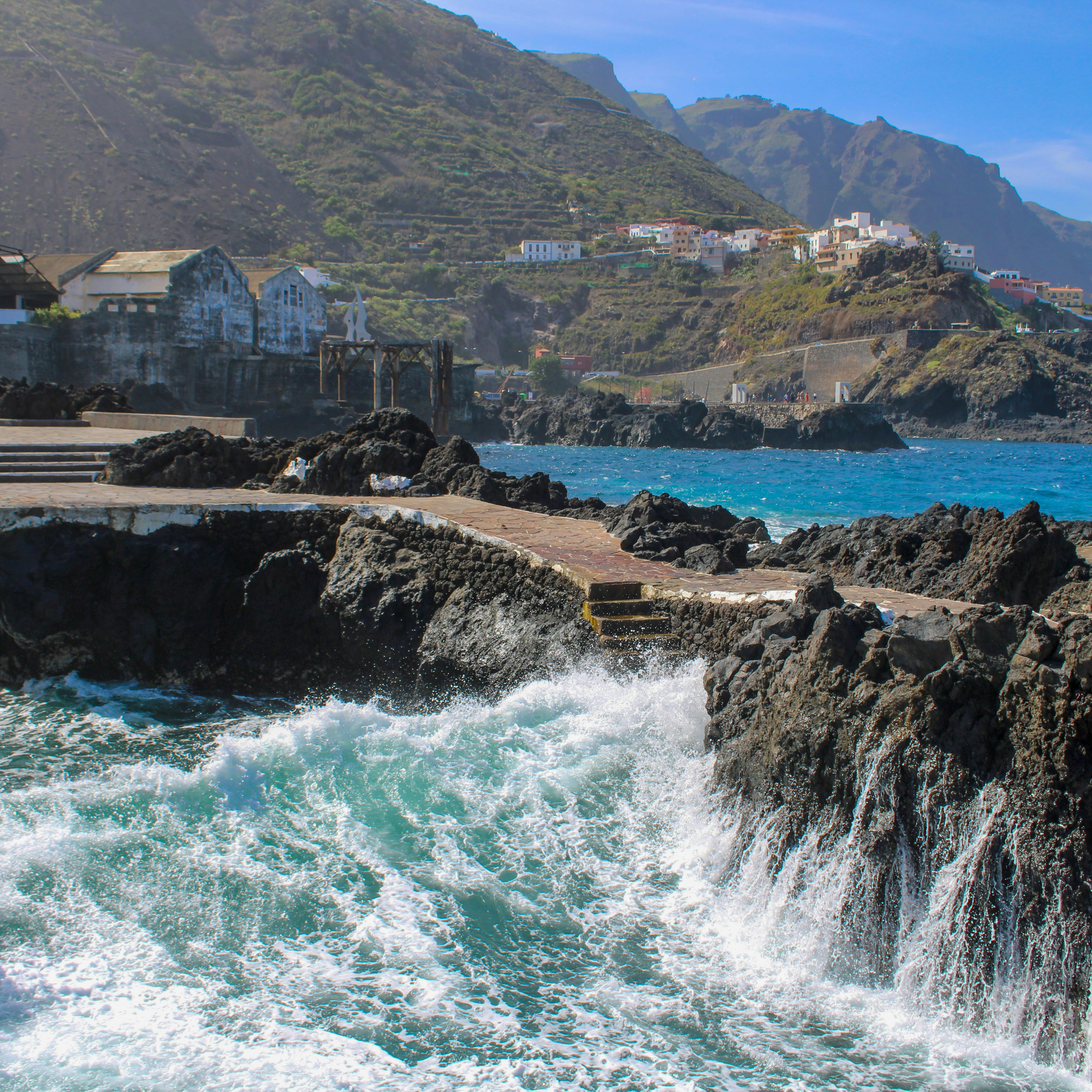 As ondas quebram contra a costa rochosa com a vila acima.