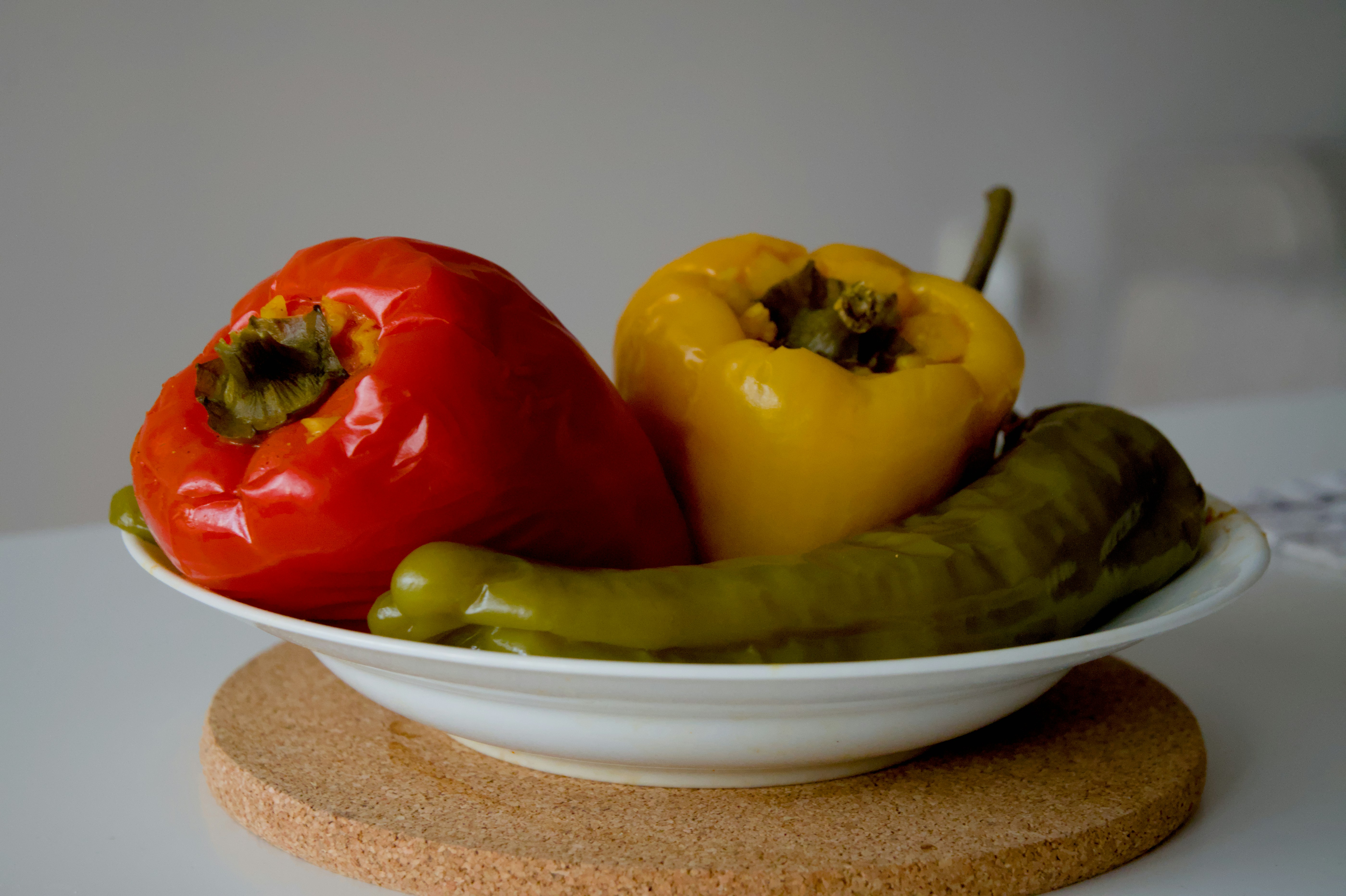 A white bowl with red, yellow, and green peppers.