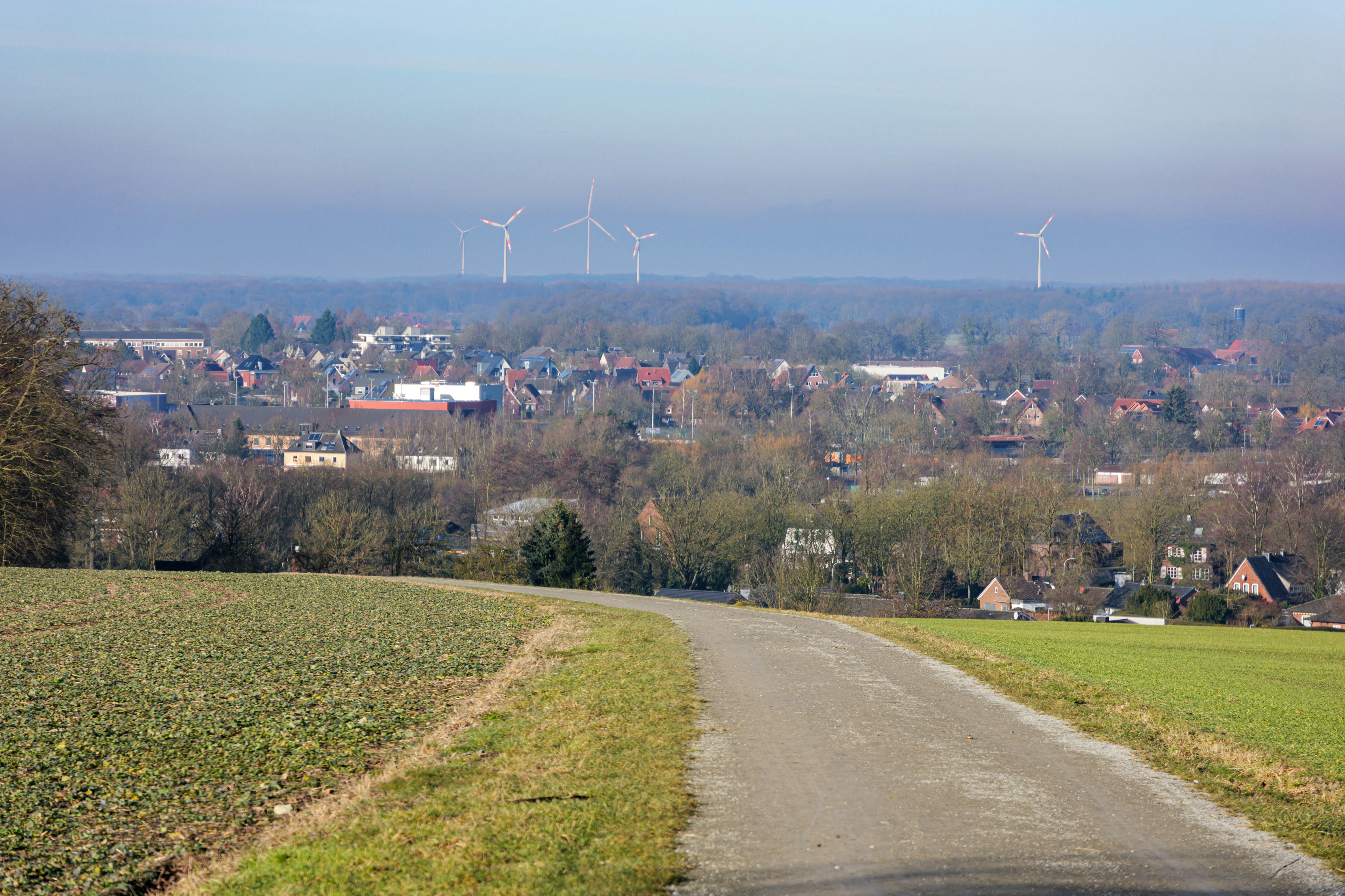 A winding road leads to a distant town with windmills.