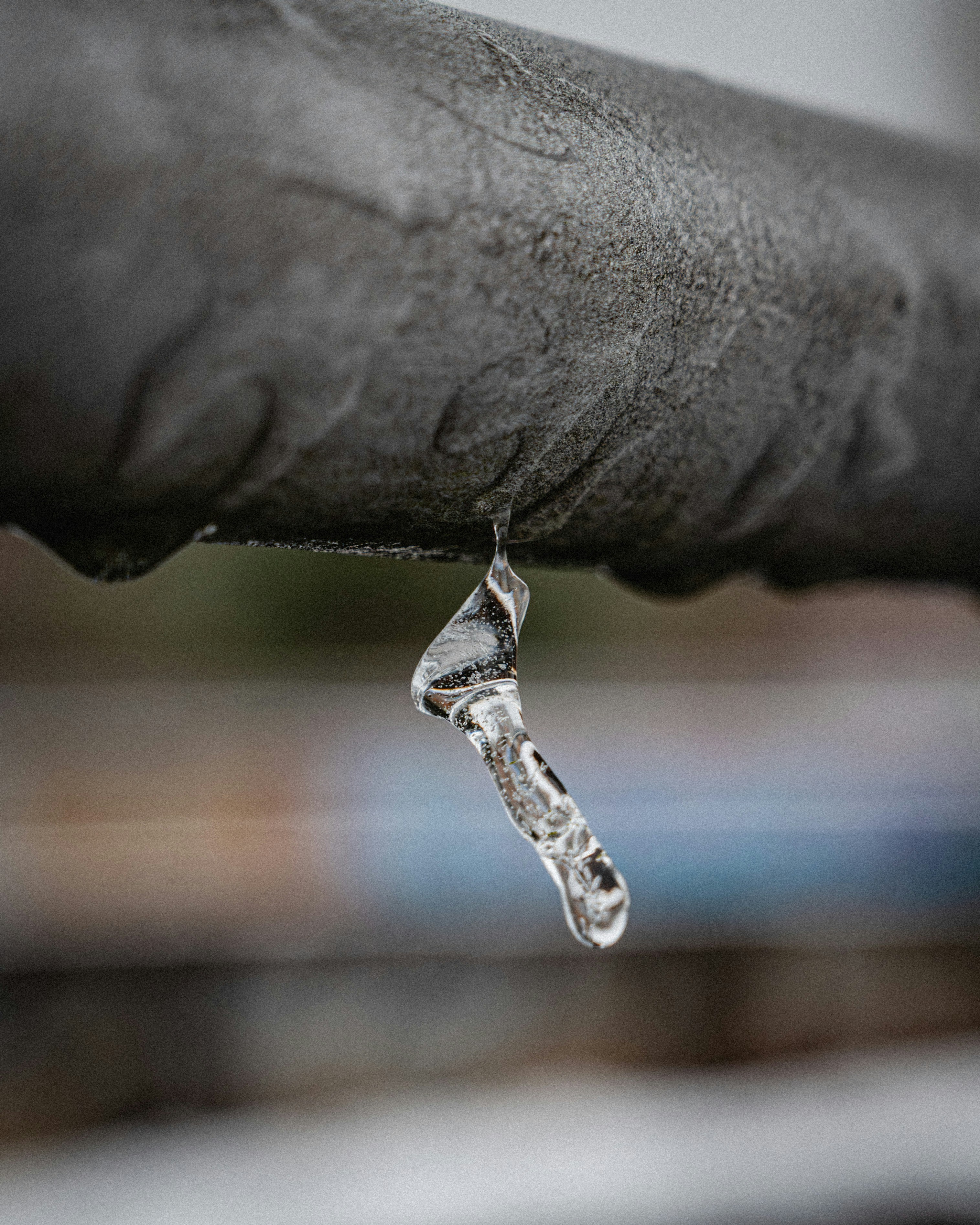 A single icicle hangs from a pipe